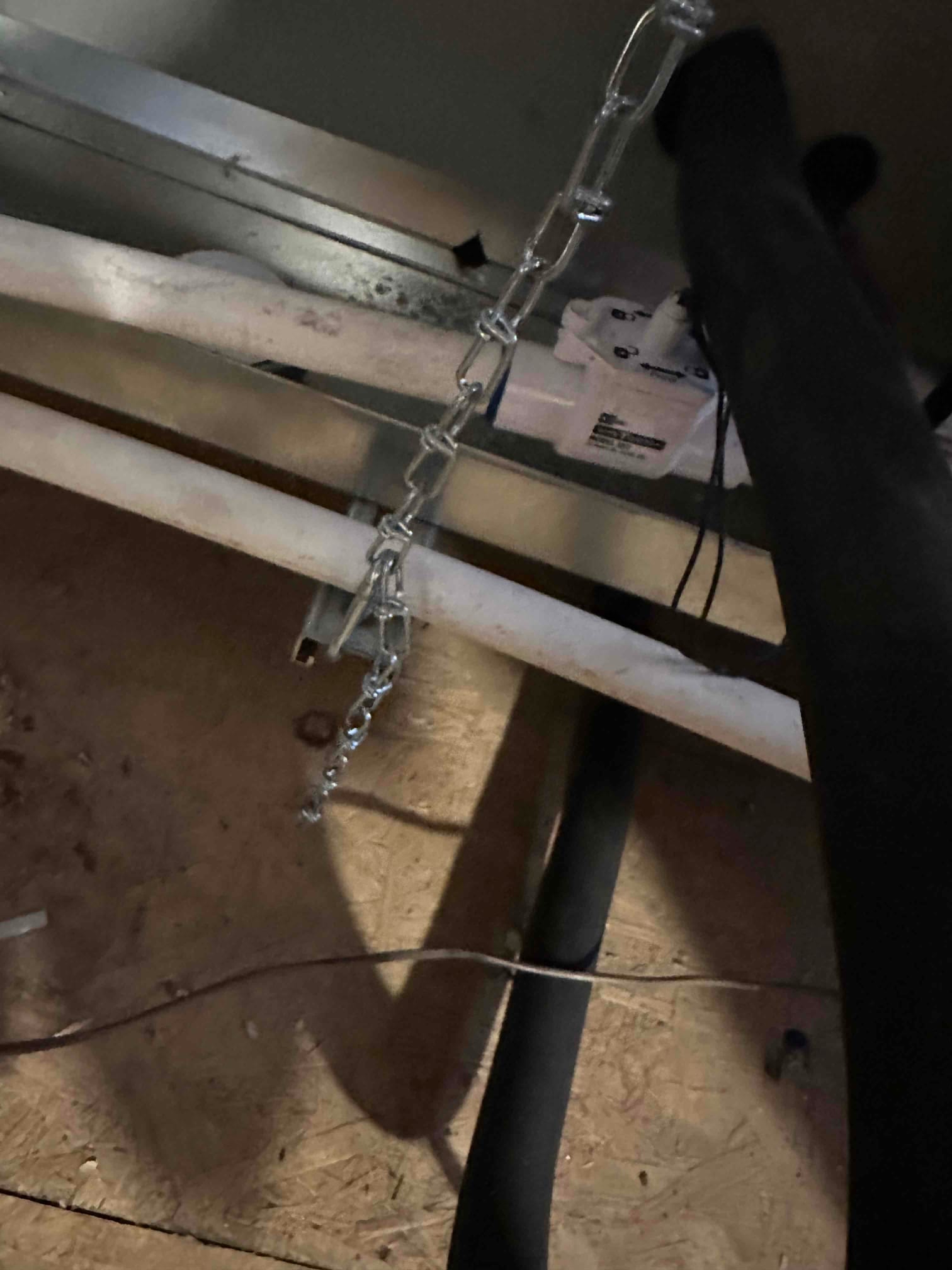 Condensate drain lines and a safety float switch installed beneath a horizontal air handler in the attic.
