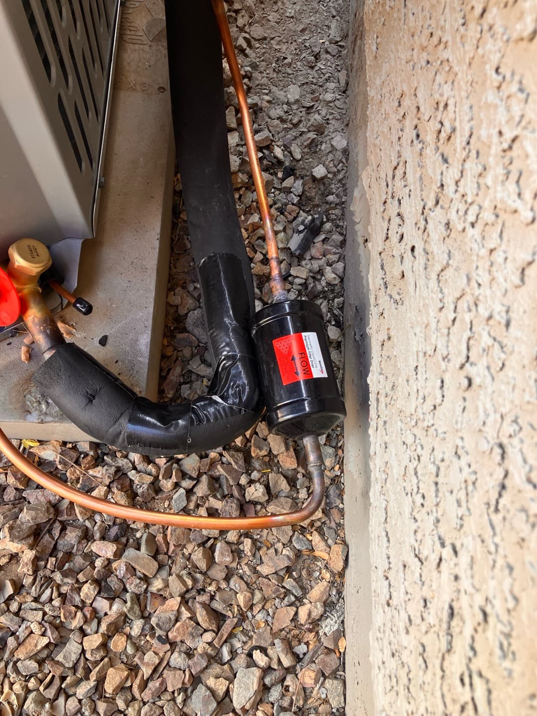 Liquid line filter-drier brazed into the copper refrigerant line beside the outdoor condenser with insulated suction line.