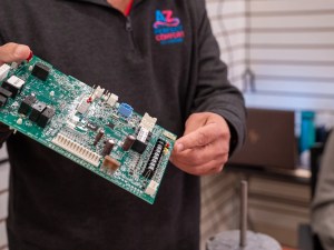 AZ Perfect Comfort technician holding an air conditioner control board removed during a repair