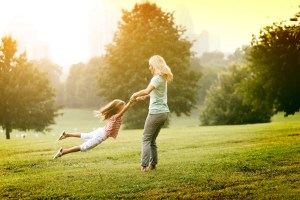 Mother and daughter enjoying a warm sunny day in a green park.
