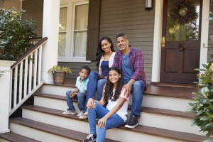 Family sitting on front steps of their home before an HVAC service appointment.
