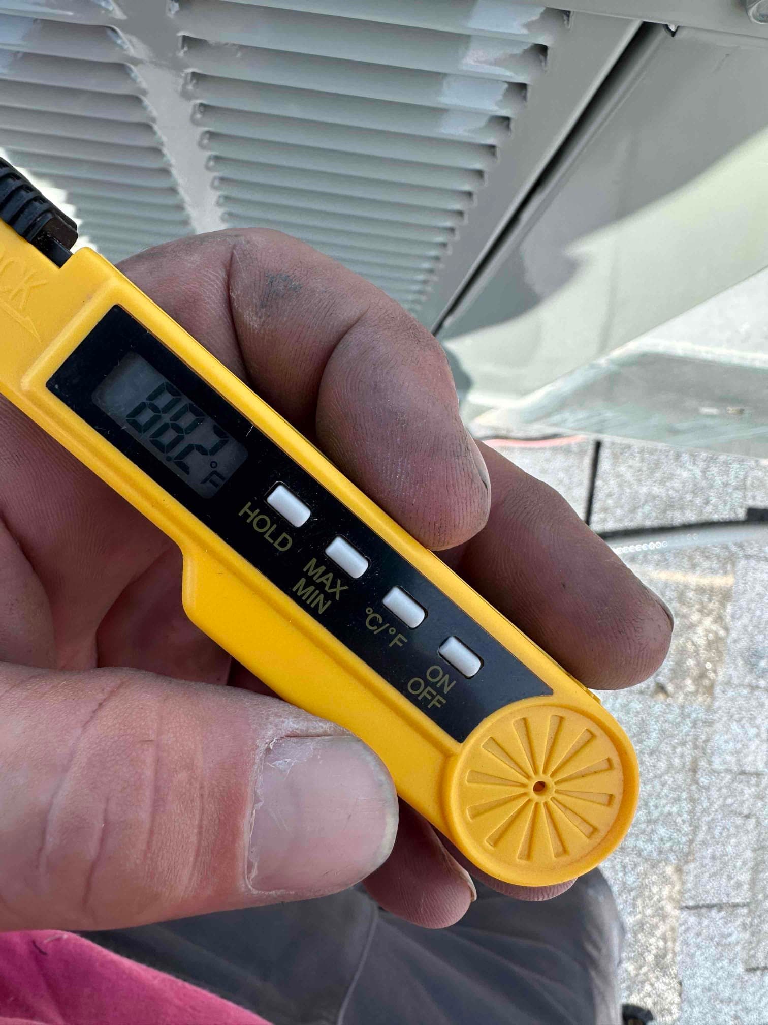 Digital thermometer shows 88.2°F, documenting a warm air temperature reading during air-side checks at the outdoor unit.
