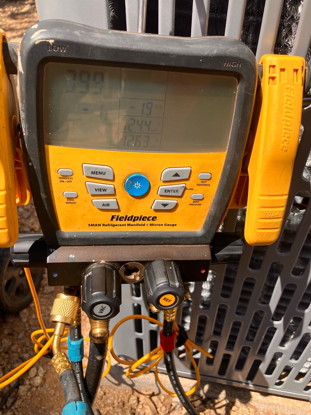 Digital manifold shows micron reading around 399, confirming a deep vacuum during system evacuation prior to refrigerant charging.