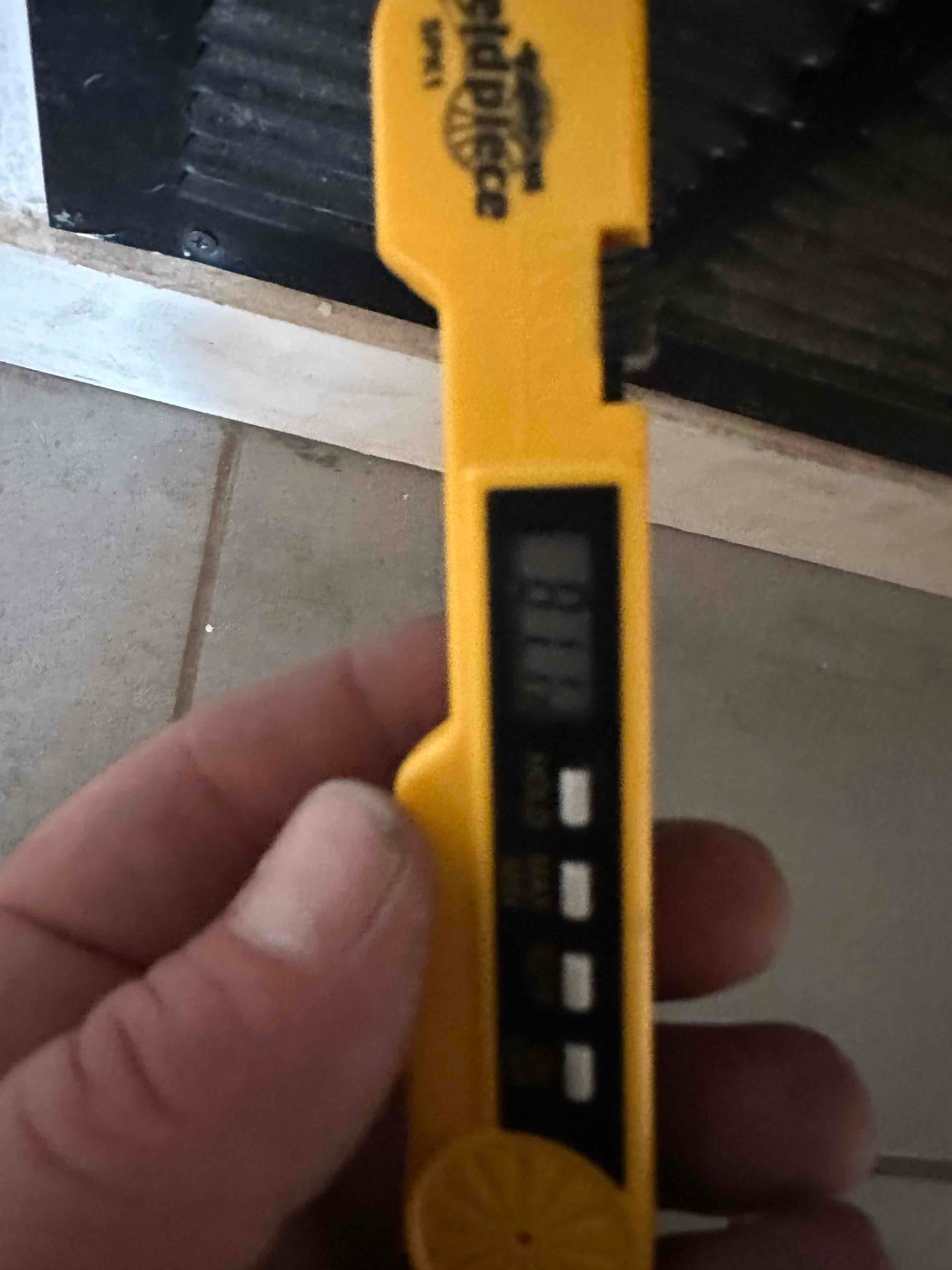 Handheld digital thermometer is positioned at a supply register grille during air temperature check after system startup.