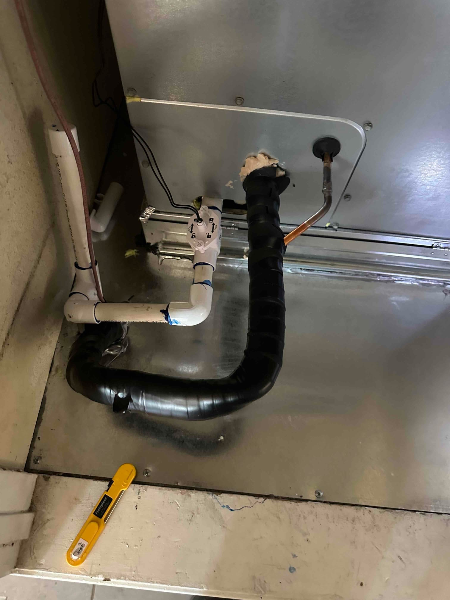 Indoor air handler base with insulated suction line, copper liquid line, and newly plumbed condensate drain with cleanout and trap.