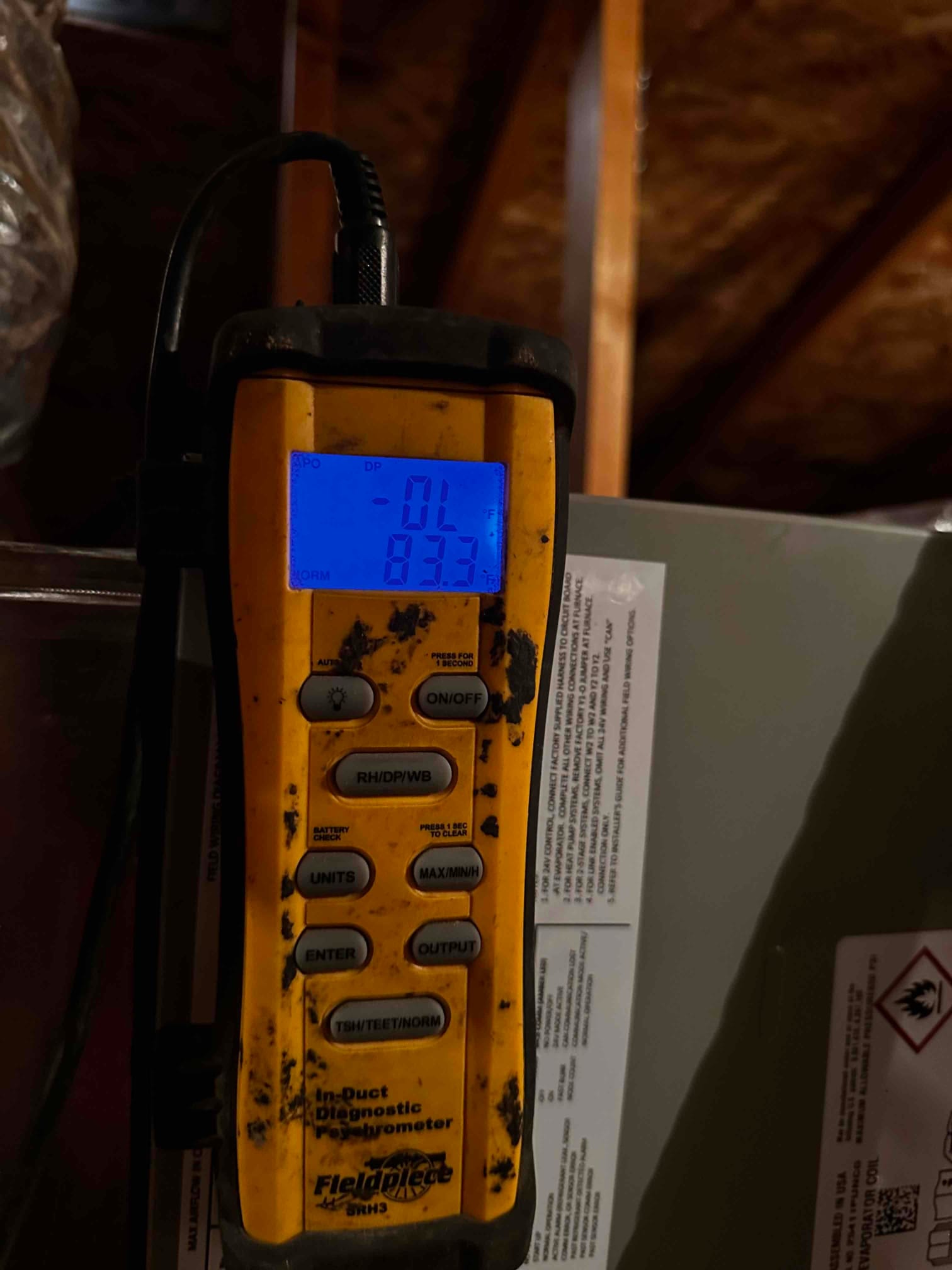 Digital in-duct probe displays 83.7°F air temperature during air-side commissioning near the air handler.
