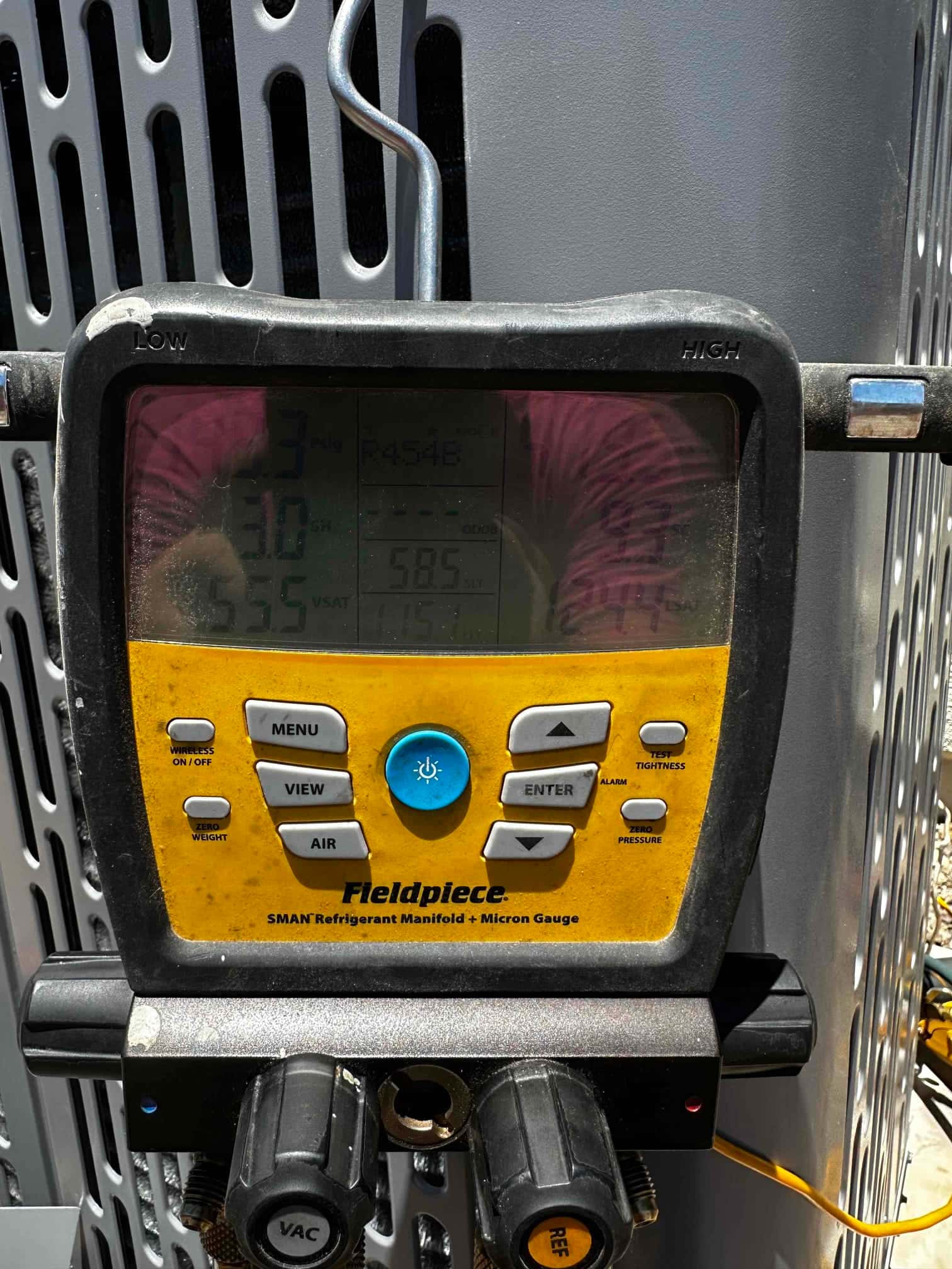 Digital manifold attached at the outdoor unit shows operating pressures while commissioning the new air conditioning system.