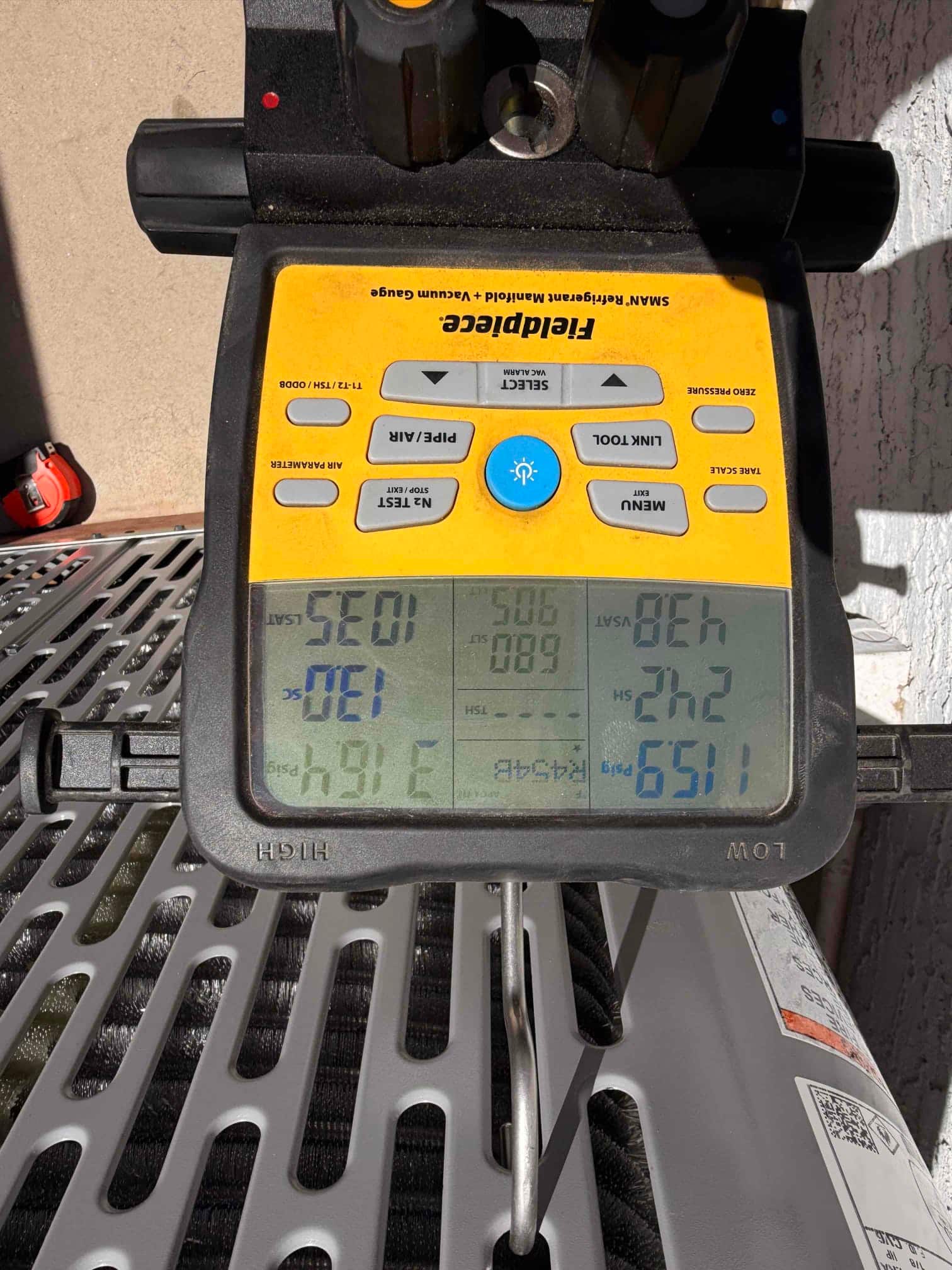Digital manifold gauges on the condenser show operating pressures with distinct low and high readings during system commissioning.