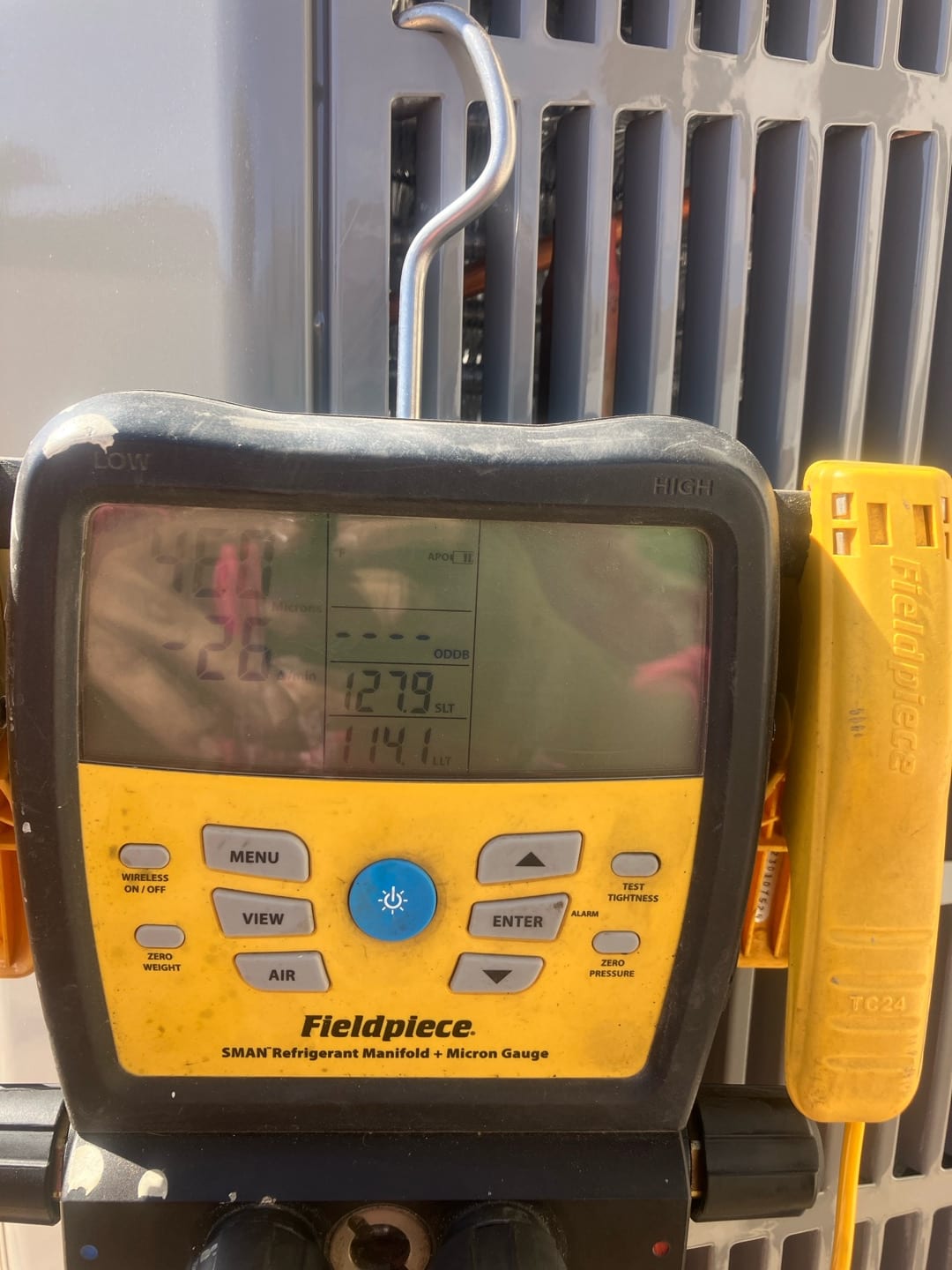 Digital manifold gauges mounted on the outdoor unit show equal high pressure on both sides during a nitrogen pressure test.