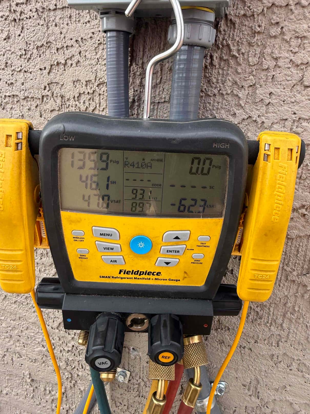 Digital manifold shows R-410A with low-side pressure at 135.9 PSI and high-side at 0 PSI during system commissioning check.