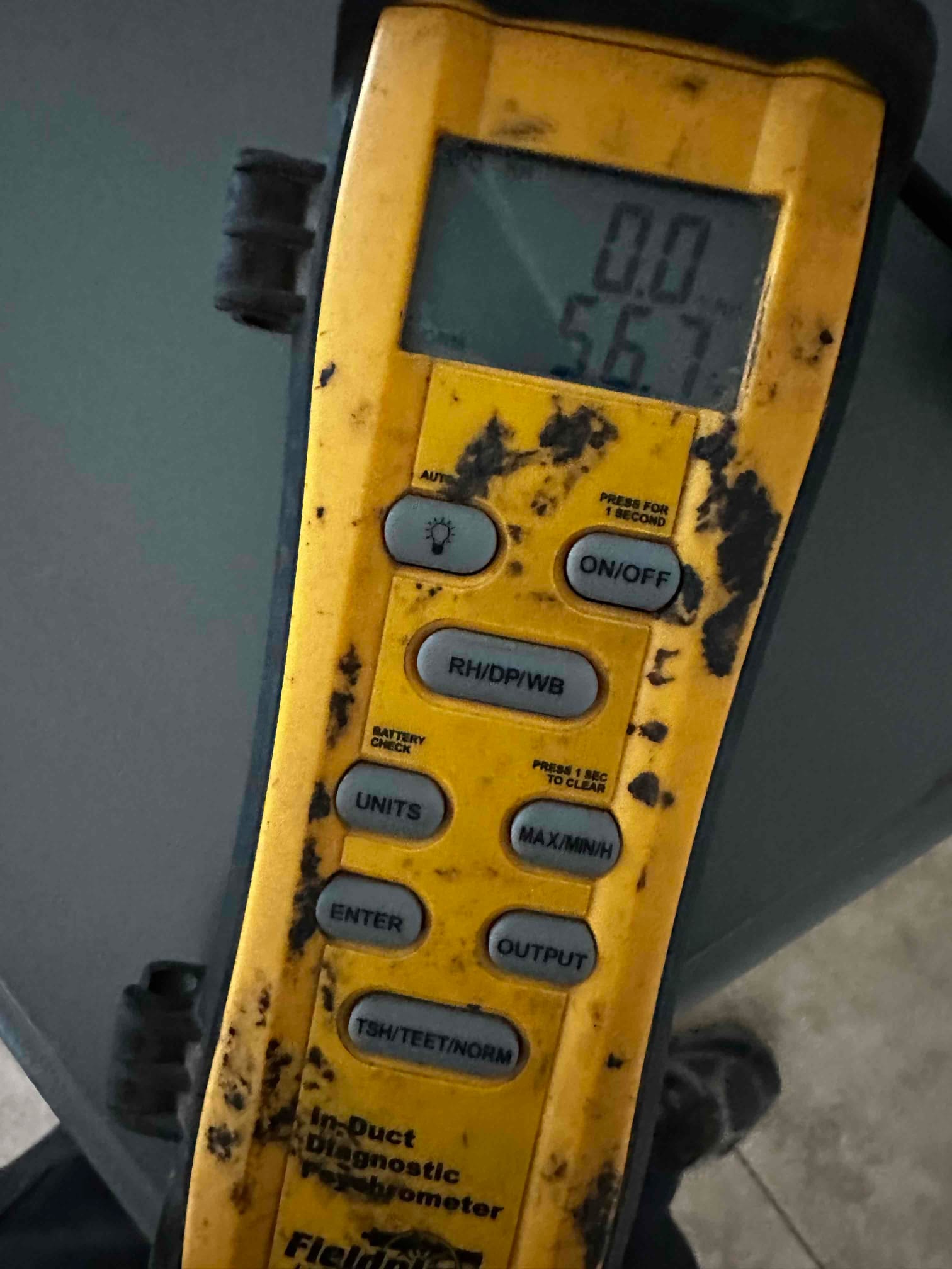 Digital thermometer displays 56.7 degrees while measuring air temperature during commissioning of the mini-split system.