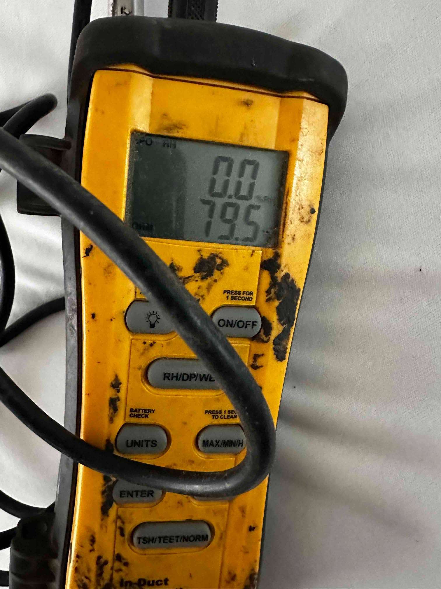 Digital thermometer displays 79.5 degrees, documenting return air temperature during commissioning of the mini-split system.