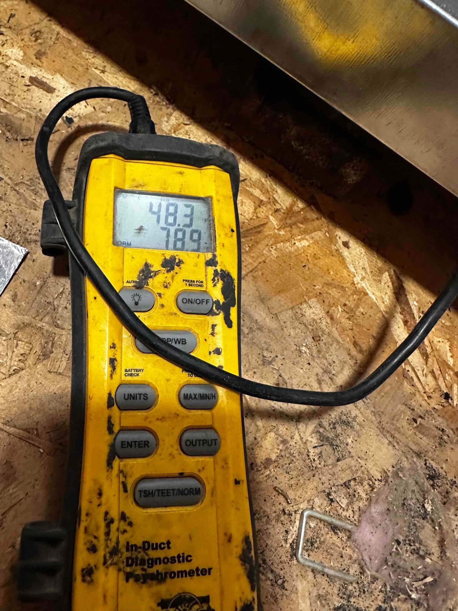 Digital thermometer shows 48.3 degrees on the display during air temperature measurement at the HVAC system.