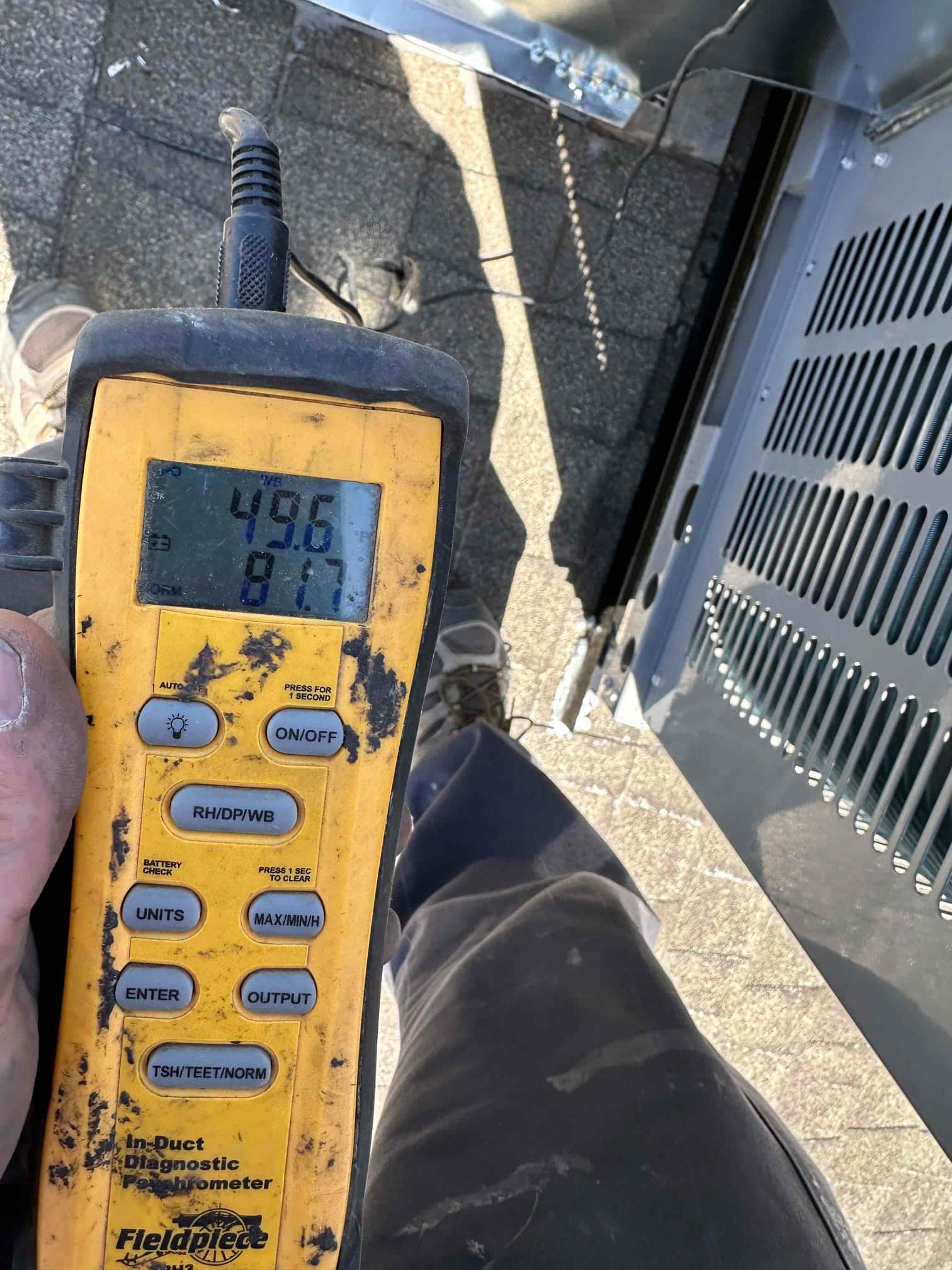 Digital thermometer shows 49.6°F supply air temperature at the package unit during commissioning checks.