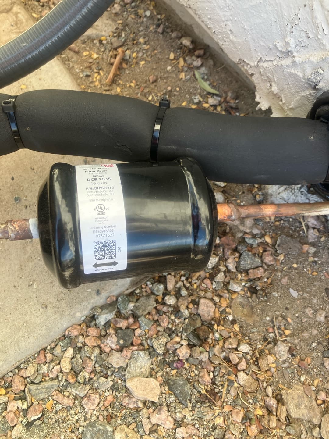 Liquid-line filter drier installed on the copper refrigerant line with insulated suction line secured by zip ties.
