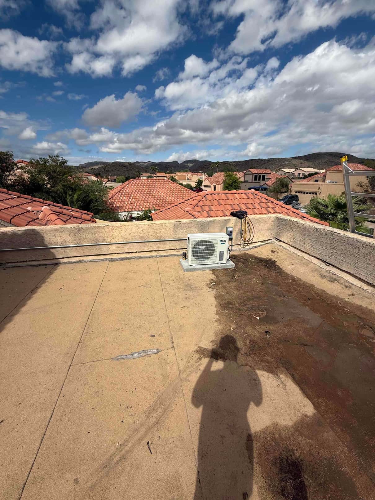 Mini-split outdoor condenser installed on a rooftop pad with sealed wall penetration and routed line set.