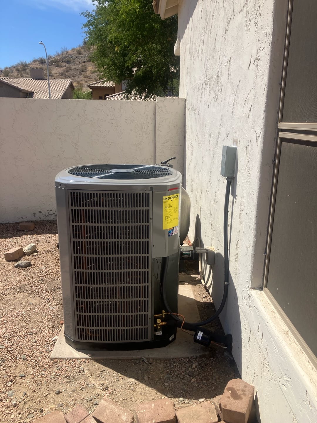 New outdoor heat pump condenser set on a level pad with insulated line set, filter dryer, and electrical disconnect mounted.