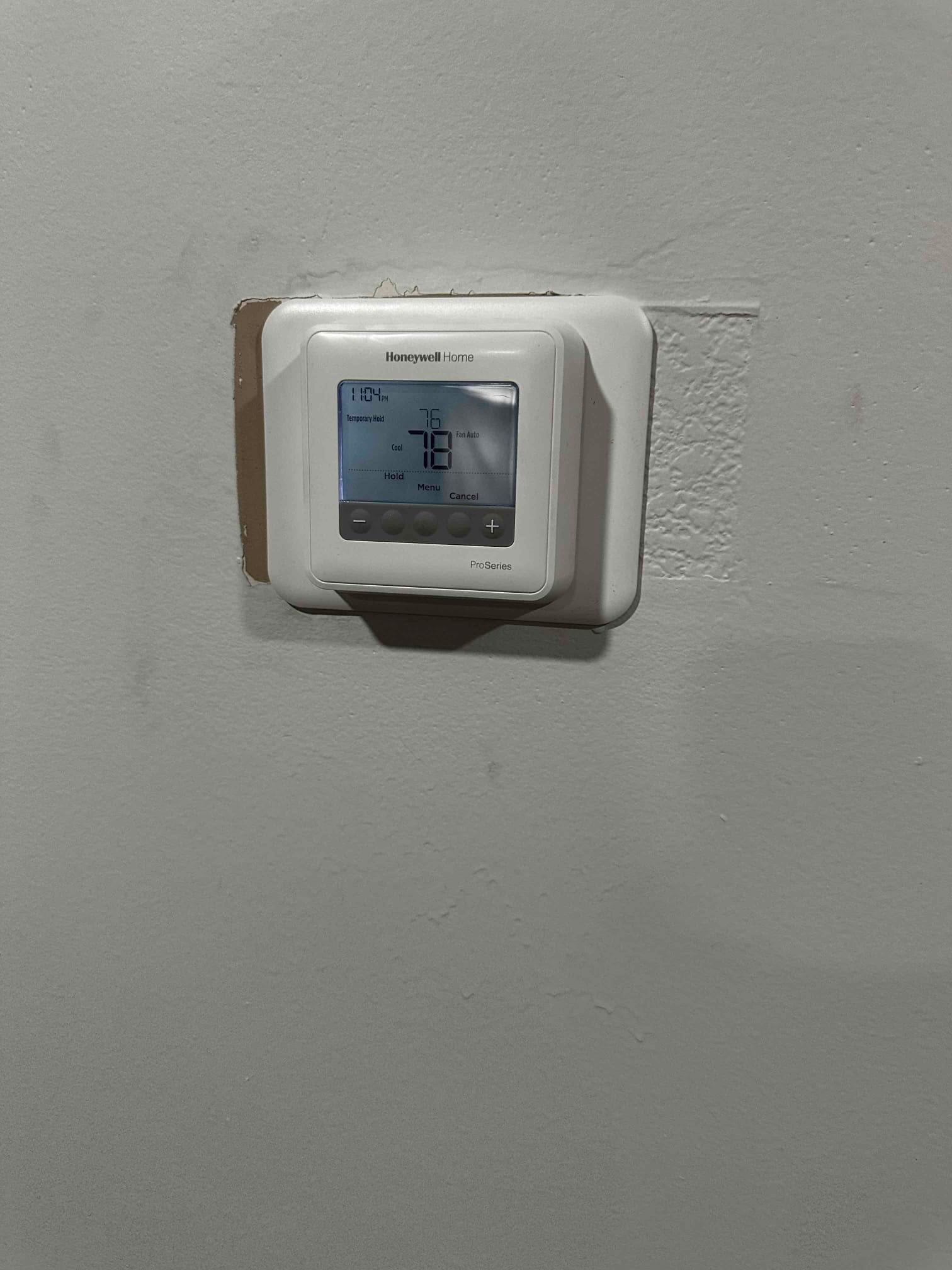 Wall-mounted digital thermostat installed and powered, display showing system mode and temperature settings after commissioning.