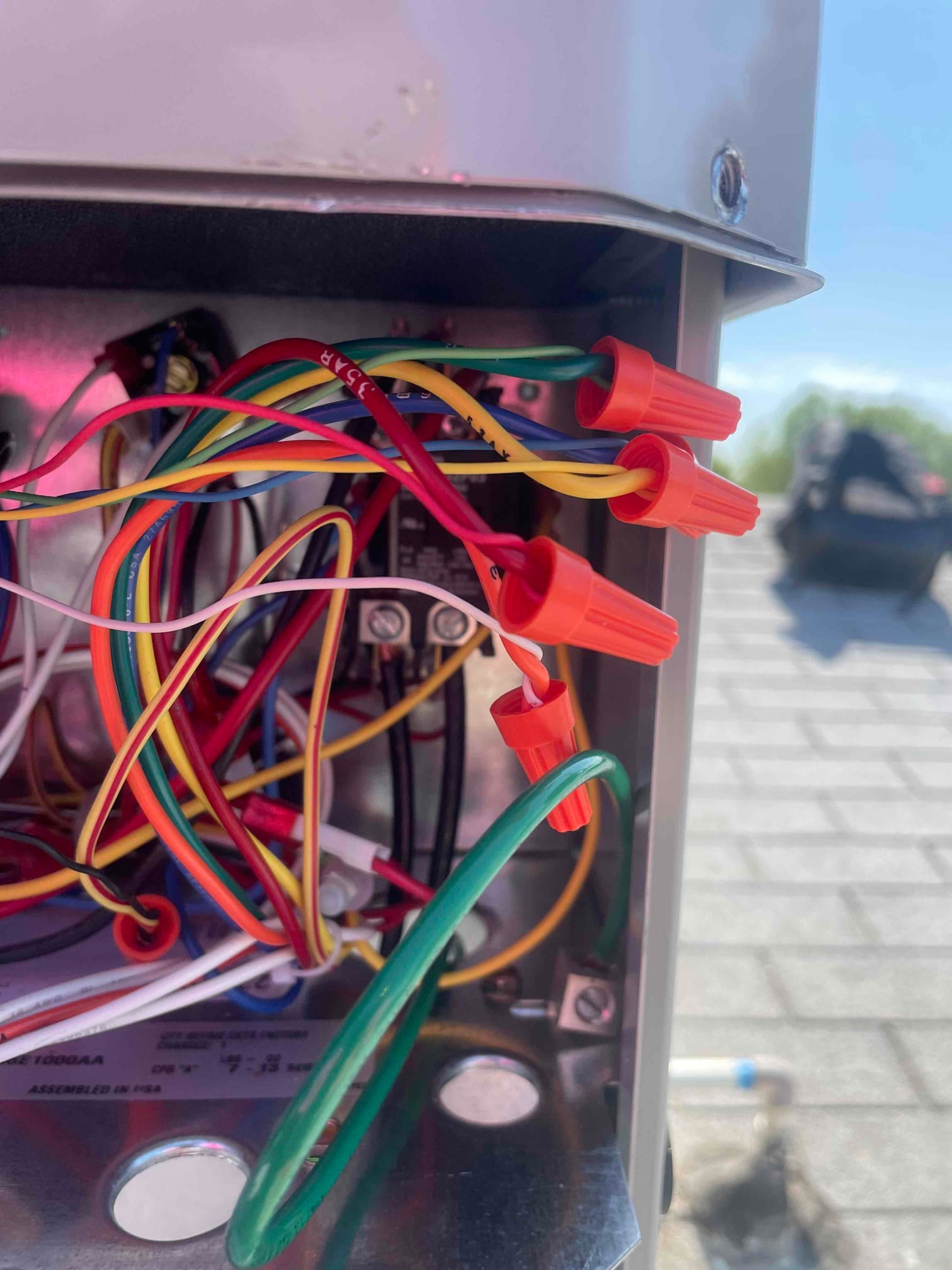 Close-up of condenser control compartment showing low-voltage wiring connections secured with wire nuts and a bonded green ground conductor.
