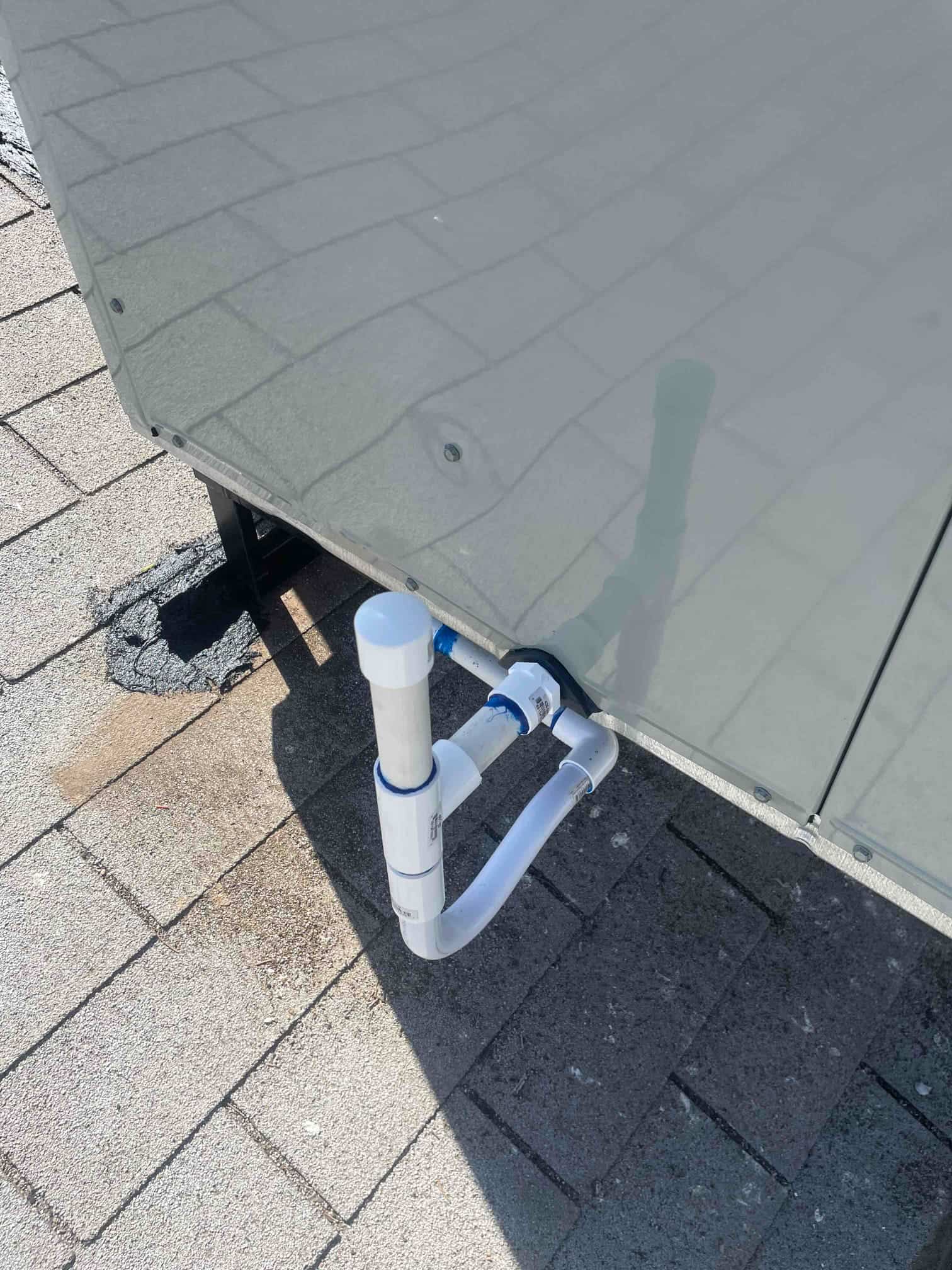 Condensate drain assembly with PVC piping exits the rooftop unit cabinet, sealed penetration, and clean trap configuration.