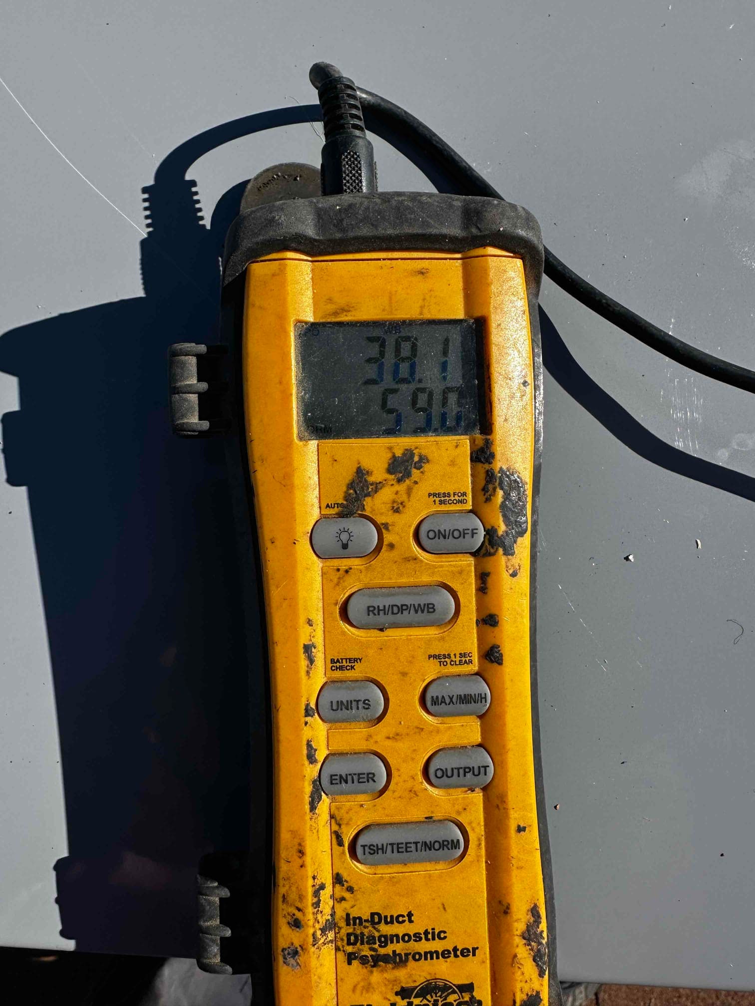 Digital psychrometer displays 38.1 and 59.0 on its screen during air-side commissioning measurements at the new installation.
