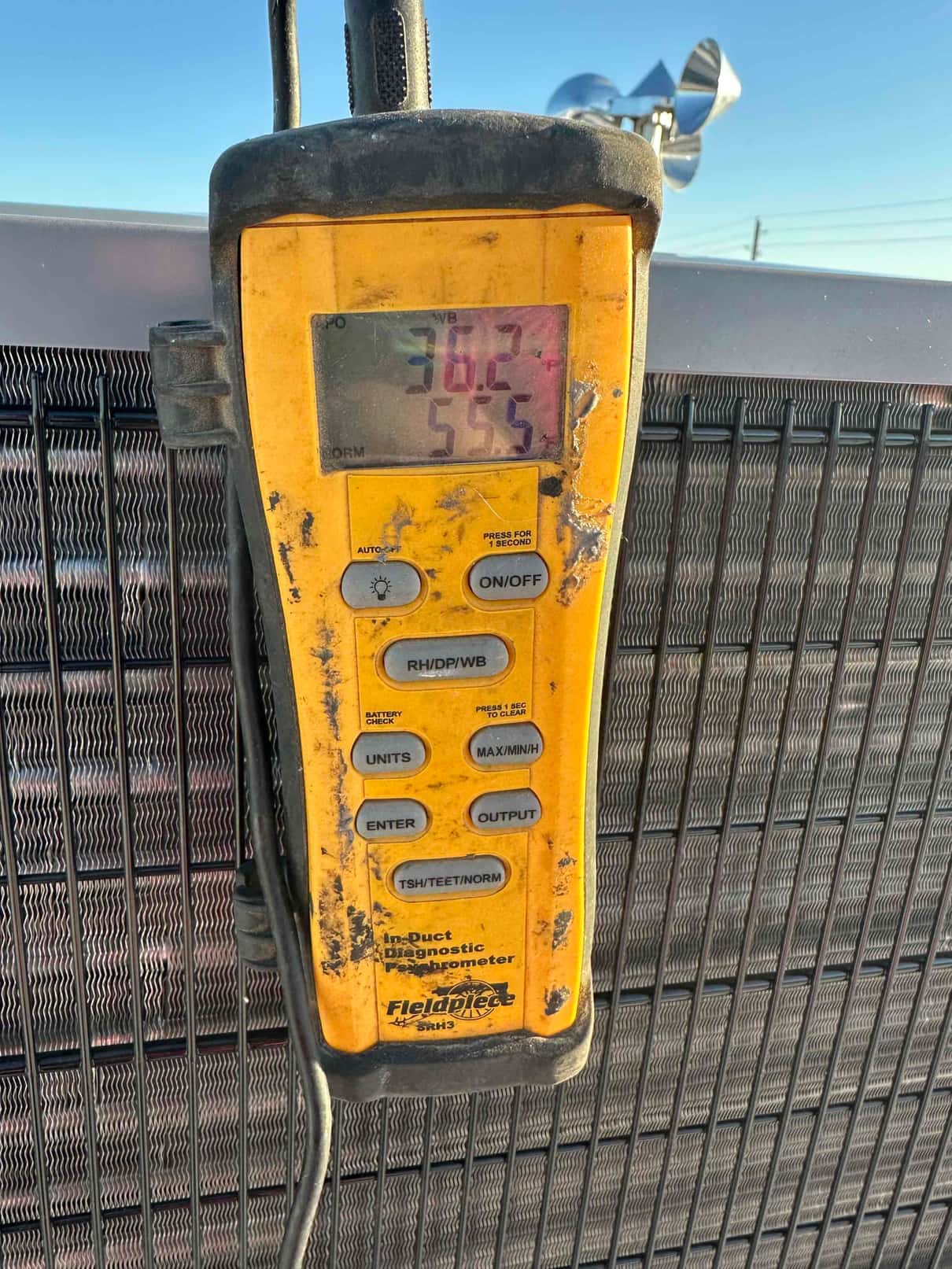 Digital thermometer attached at the outdoor condenser shows a 55.5 degree Fahrenheit air temperature reading on the display.