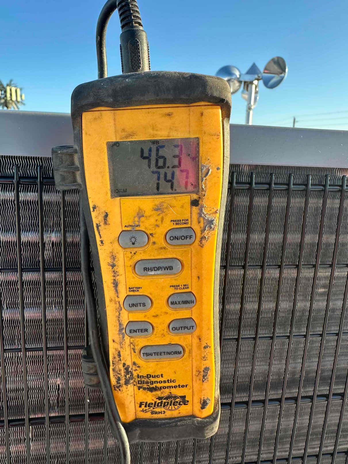 Digital thermometer displays 46.3 and 74.7 degrees during air temperature checks at the outdoor unit.