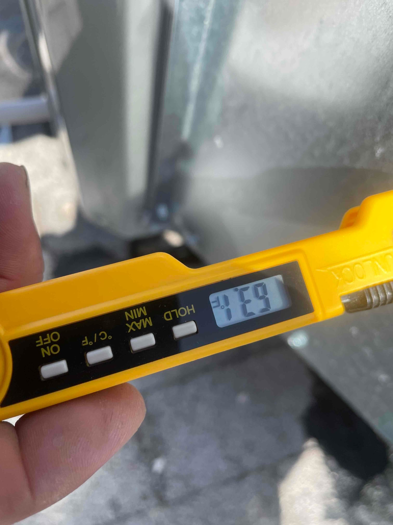Digital thermometer displays 75°F during air temperature check on the HVAC system.