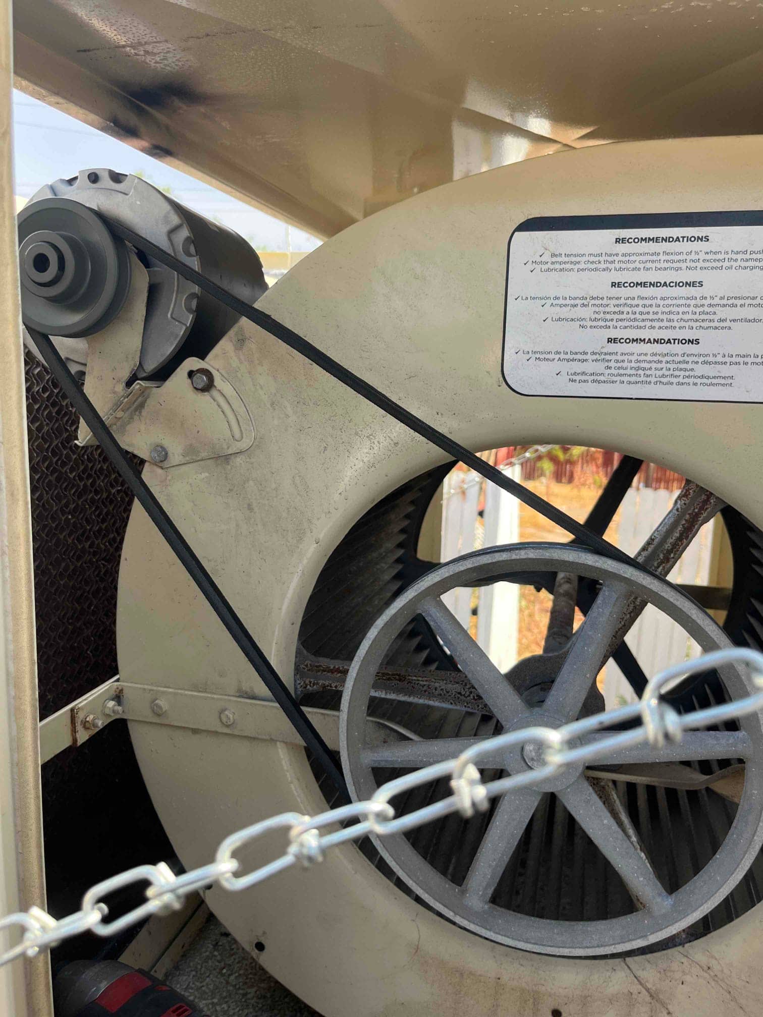 Evaporative cooler blower housing with belt-driven pulley and motor installed, showing clean belt alignment and interior blower wheel.