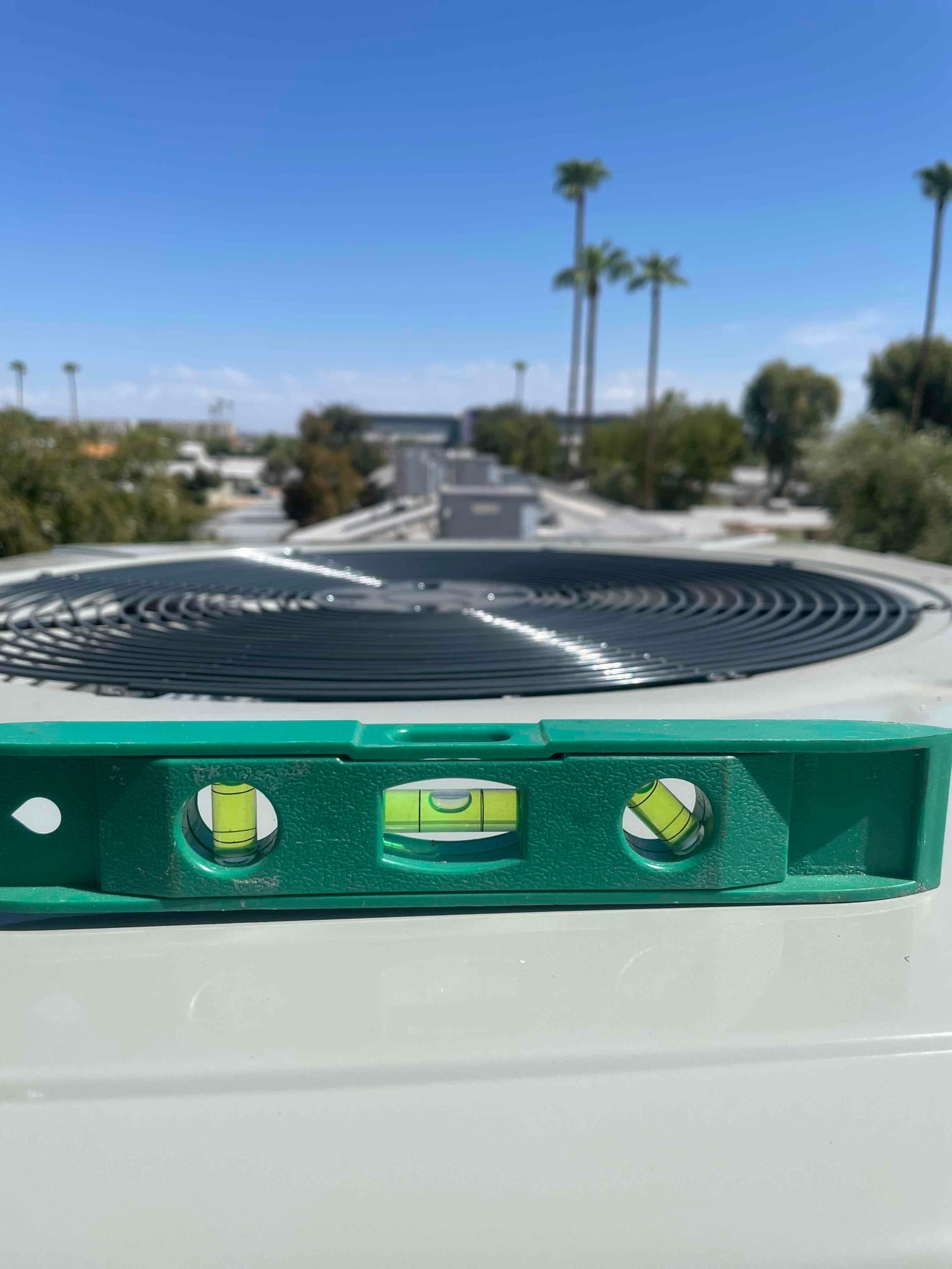 A level placed on top of a rooftop condenser cabinet confirms the unit is set plumb and level after installation.