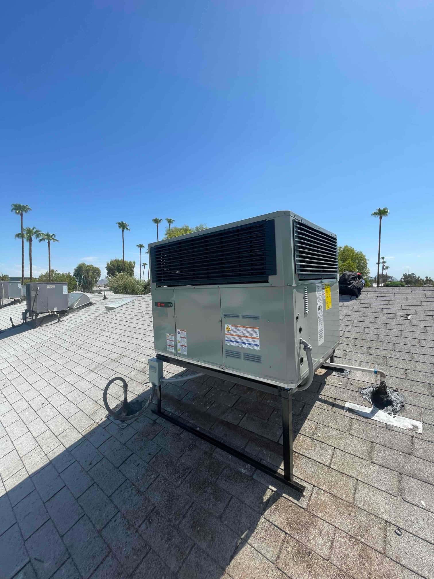 New rooftop packaged HVAC unit mounted on metal stands with roof penetrations sealed and electrical disconnect positioned nearby.