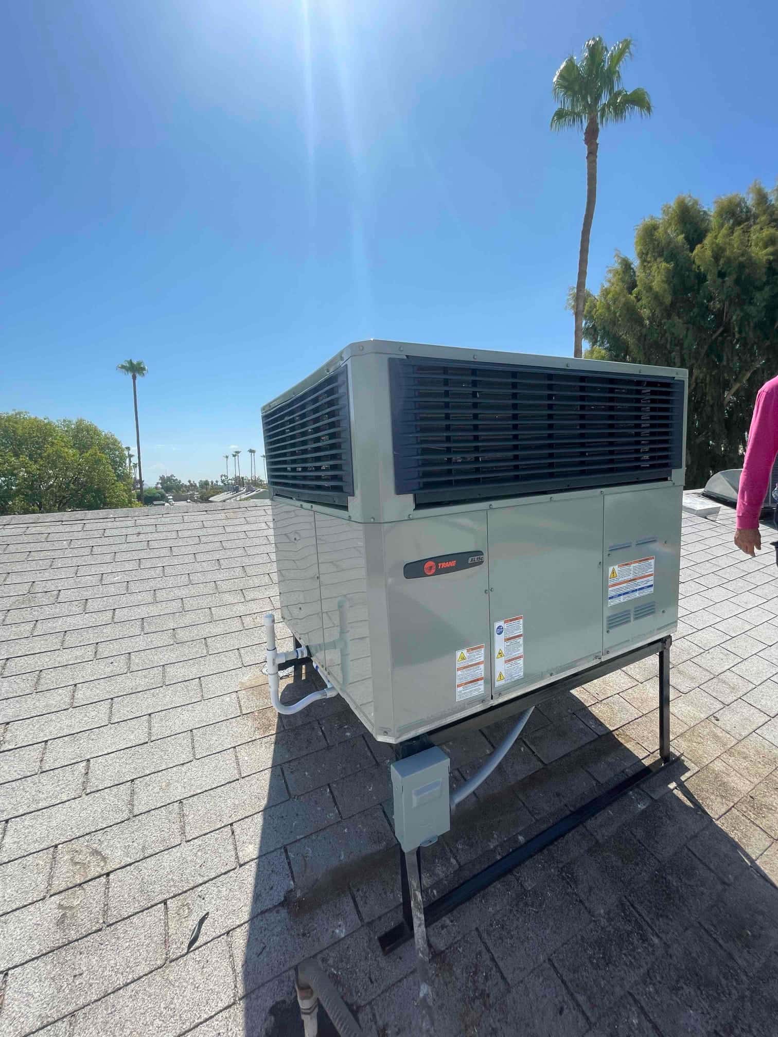 New rooftop packaged HVAC unit mounted on a steel stand with insulated drain and electrical disconnect installed.