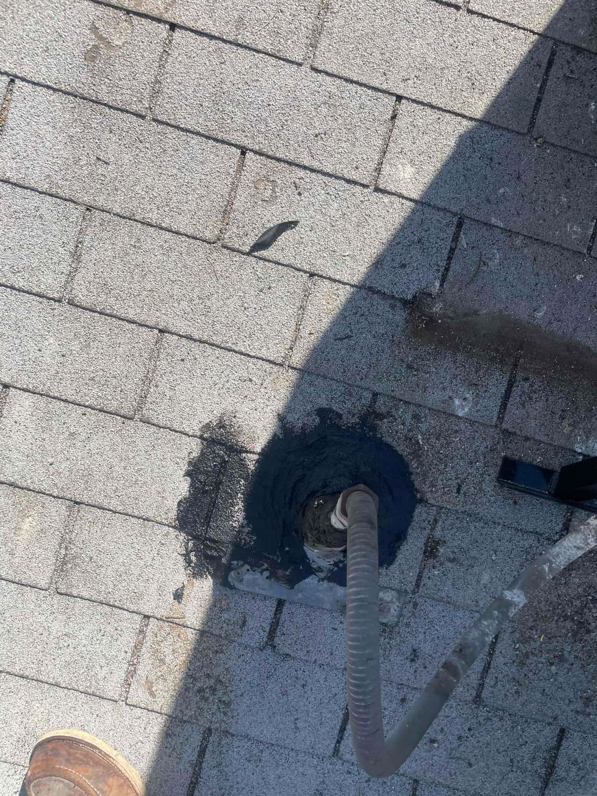 Roof penetration sealed with mastic around a flexible conduit or line set, protecting the opening against water intrusion.