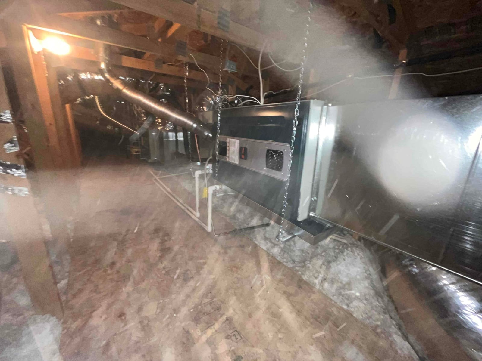 Air handler suspended in attic with new metal plenum, insulated flex ducts, and PVC condensate drain routed to trap.