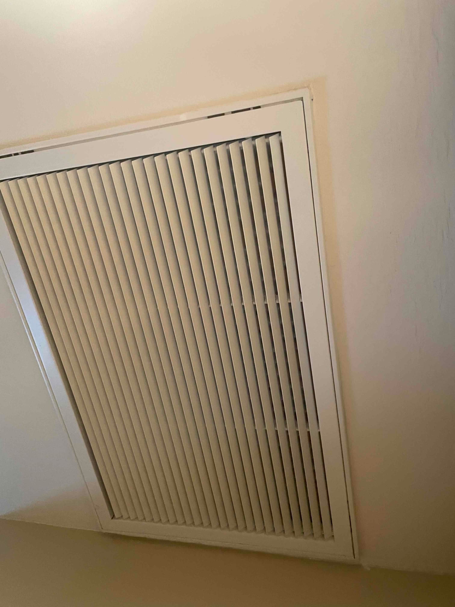 Ceiling-mounted return air grille installed flush with surrounding drywall, showing clean louvers and finished trim.