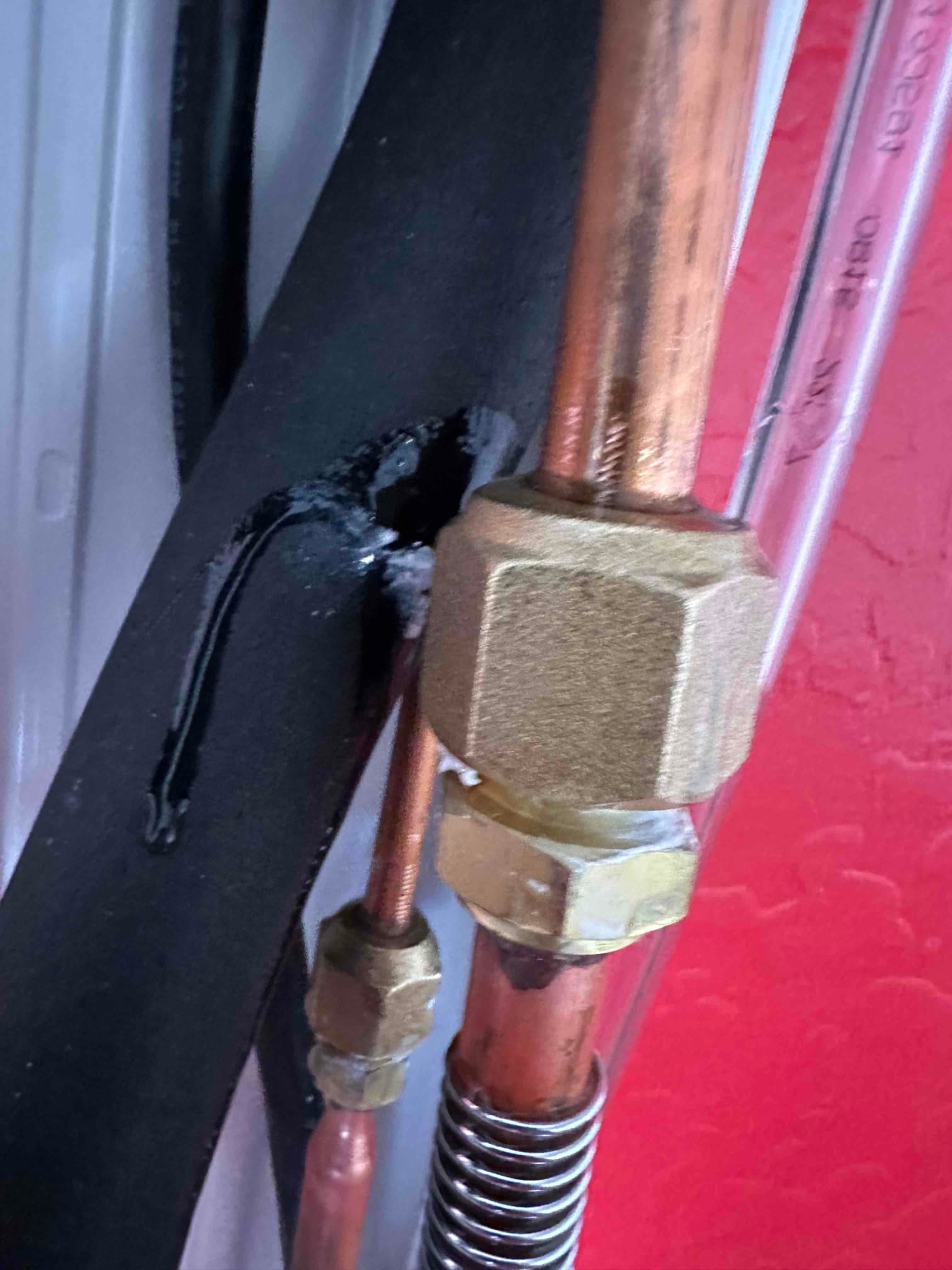Close-up of mini-split line set connections with flare nuts on copper tubing and insulated suction line.