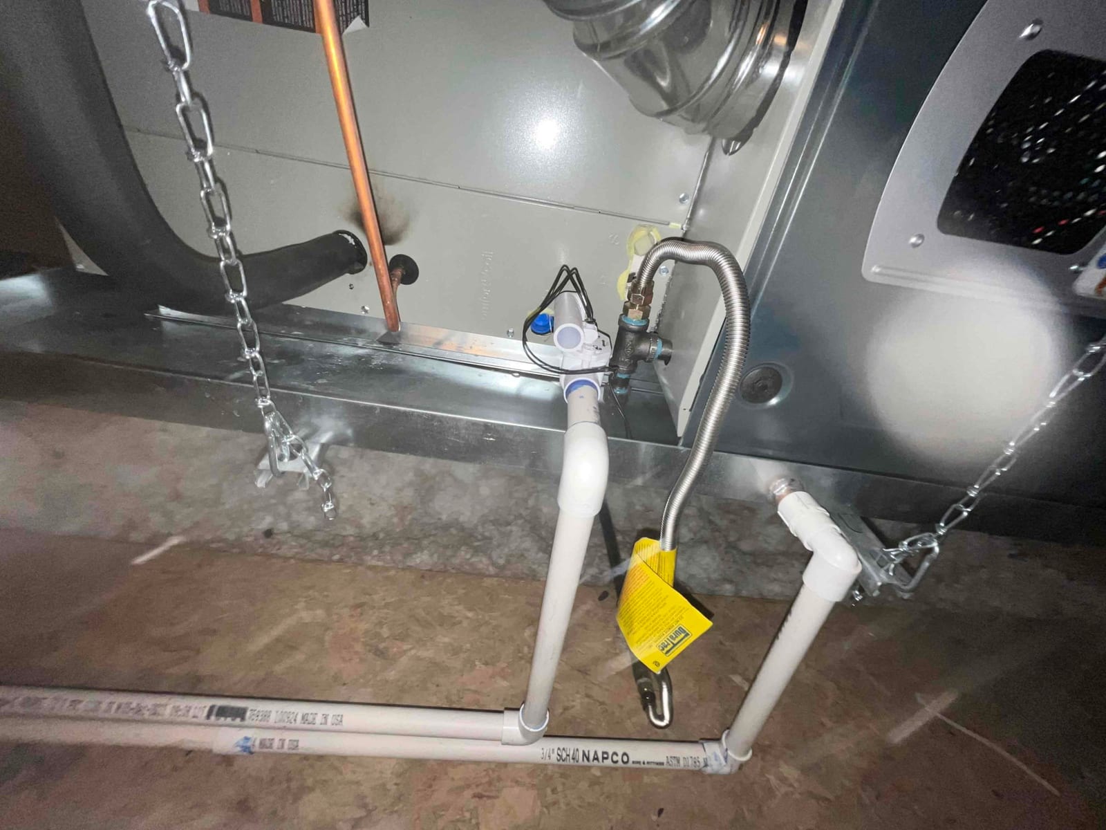 Condensate drain assembly, gas flex connector with shutoff, and suspended furnace bottom panel shown during installation.