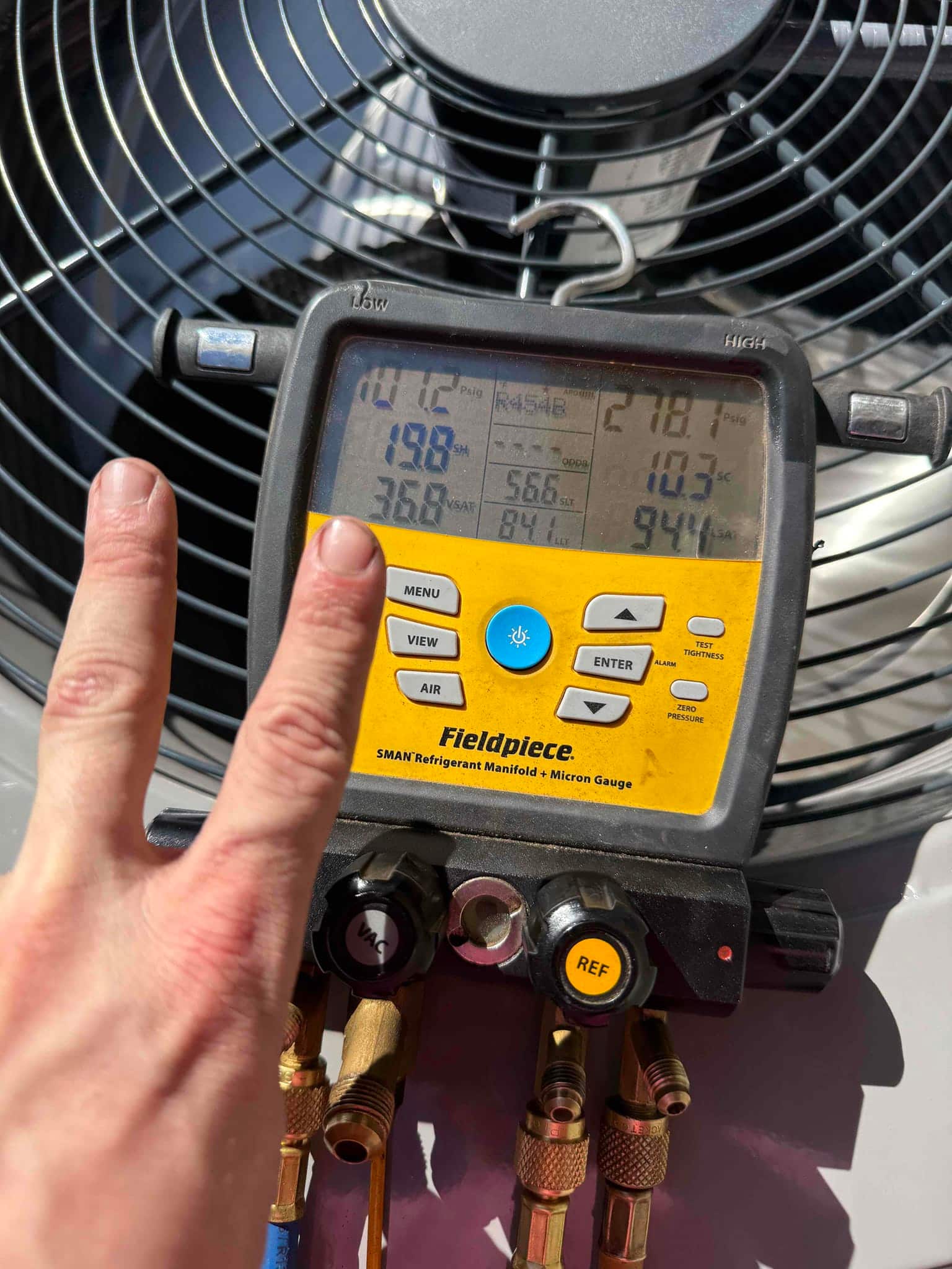 Digital manifold attached at the outdoor unit shows operating pressures and temperatures during system commissioning.