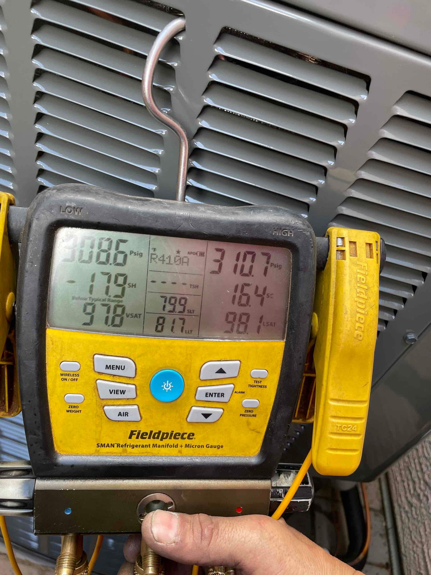 Digital manifold connected to the outdoor unit shows operating pressures and temperatures during system startup and refrigerant commissioning.