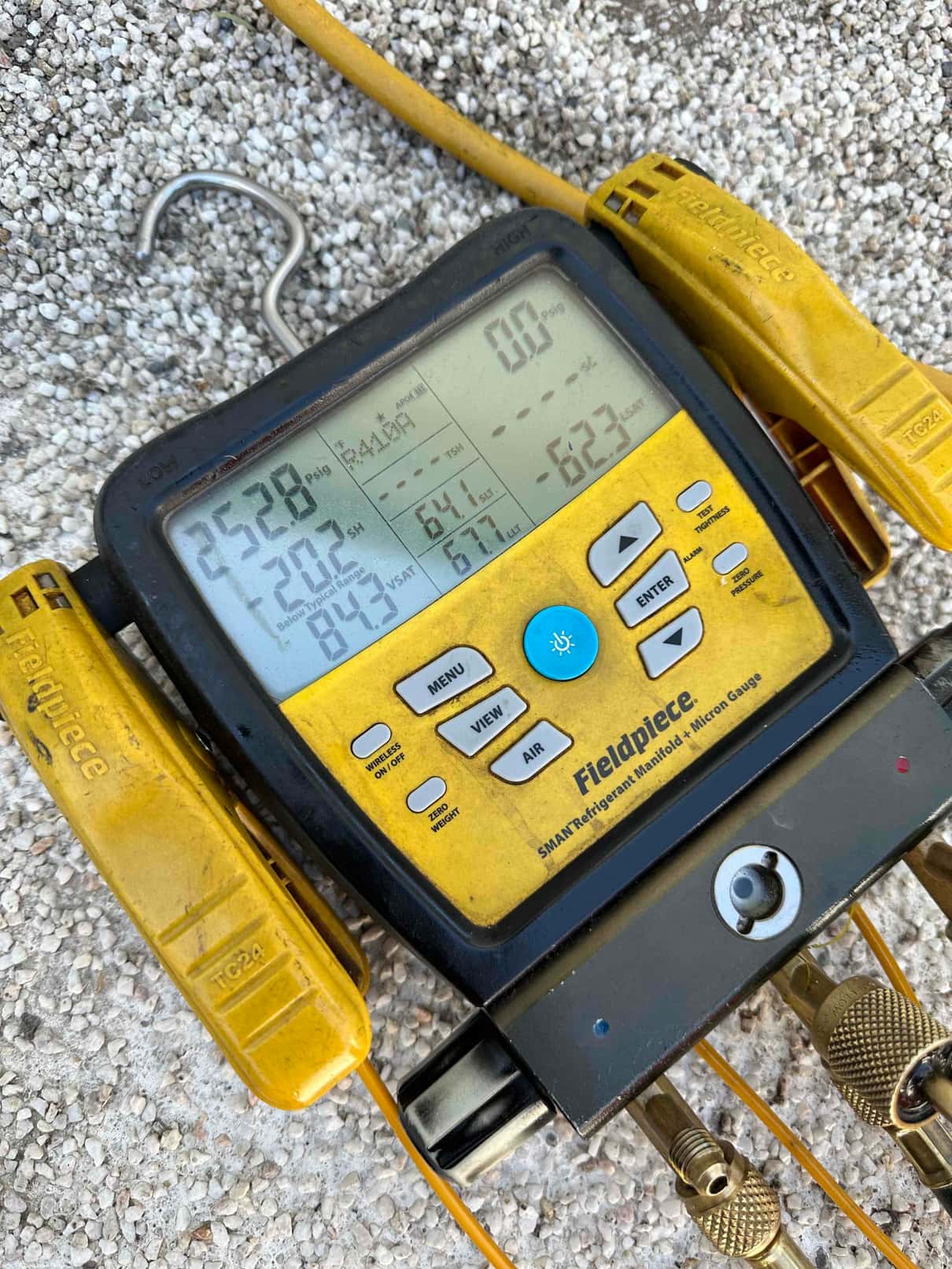 Digital manifold gauge set shows operating pressures with connected temperature clamps during system commissioning on a newly installed mini-split.