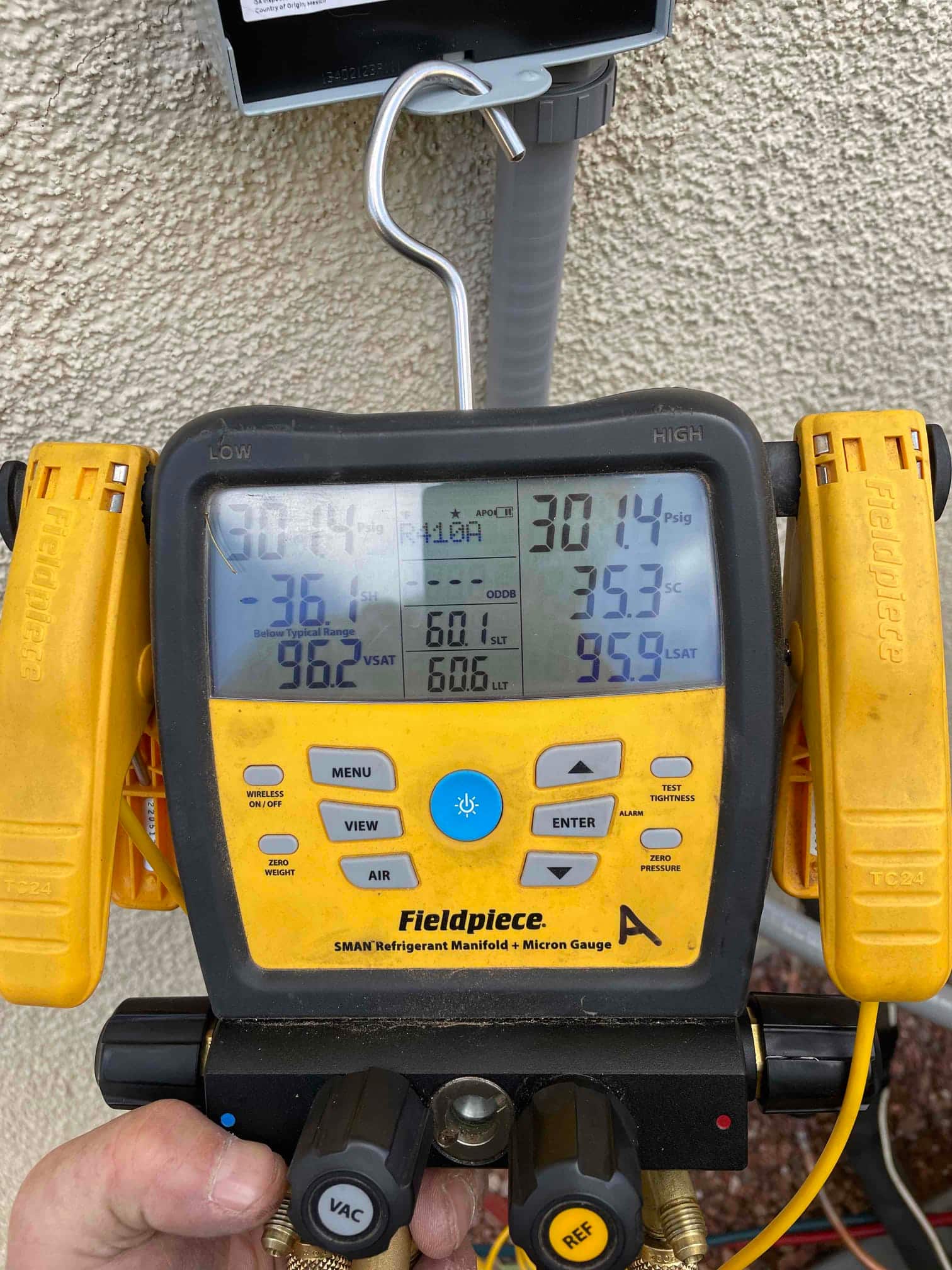 Digital manifold gauges display operating pressures while commissioning the outdoor unit during a new HVAC installation.