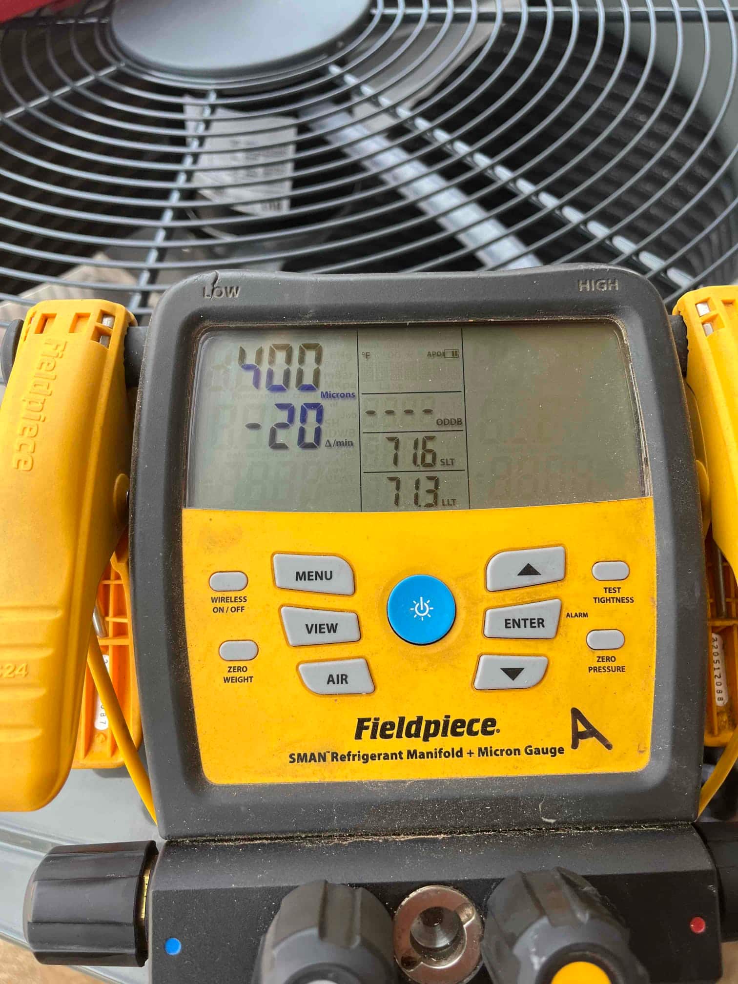 Digital manifold with micron gauge shows 400 microns during system evacuation in front of the outdoor condenser.