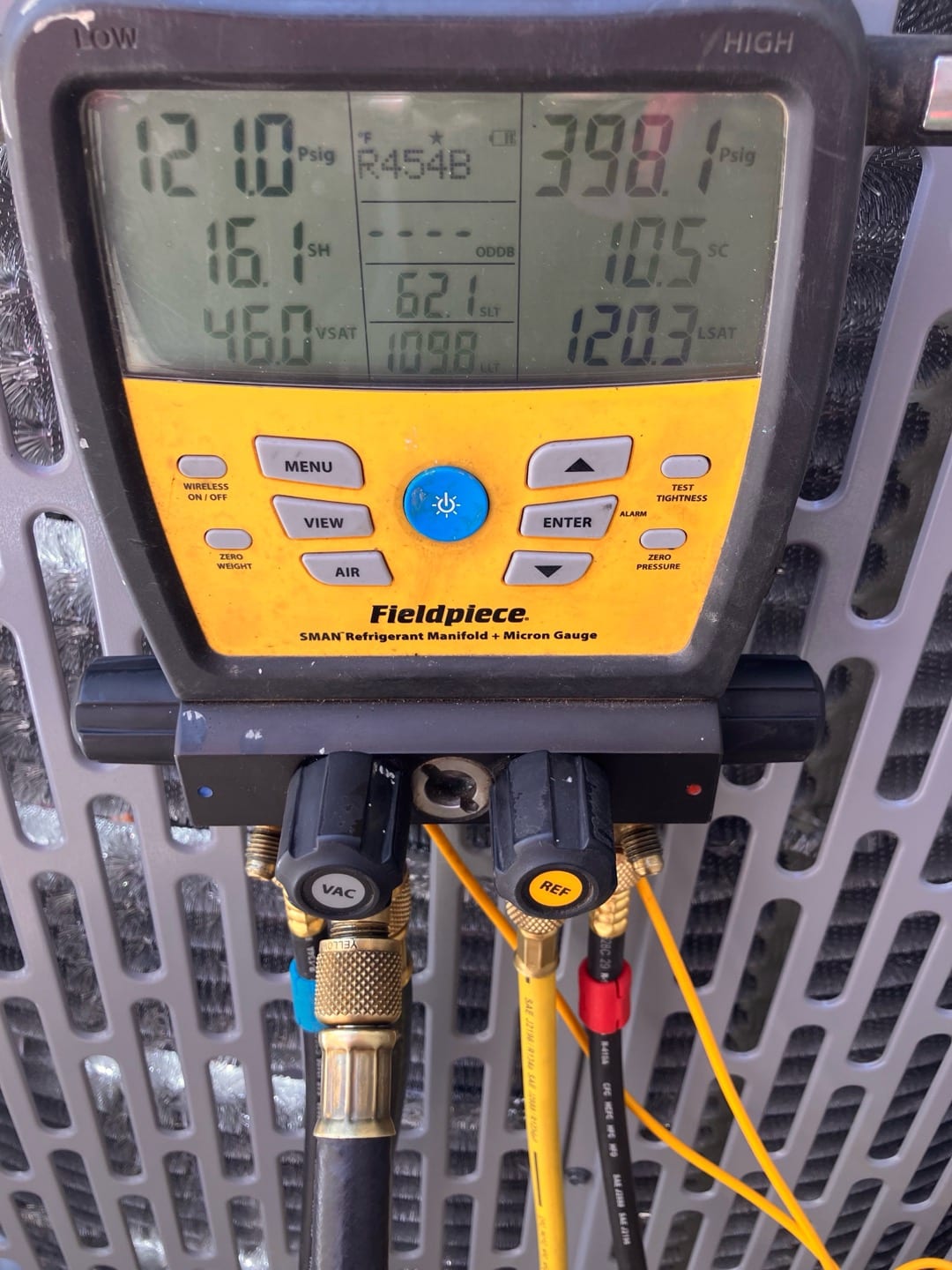 Digital manifold shows system operating pressures with R-454B refrigerant connected at the condenser during commissioning.