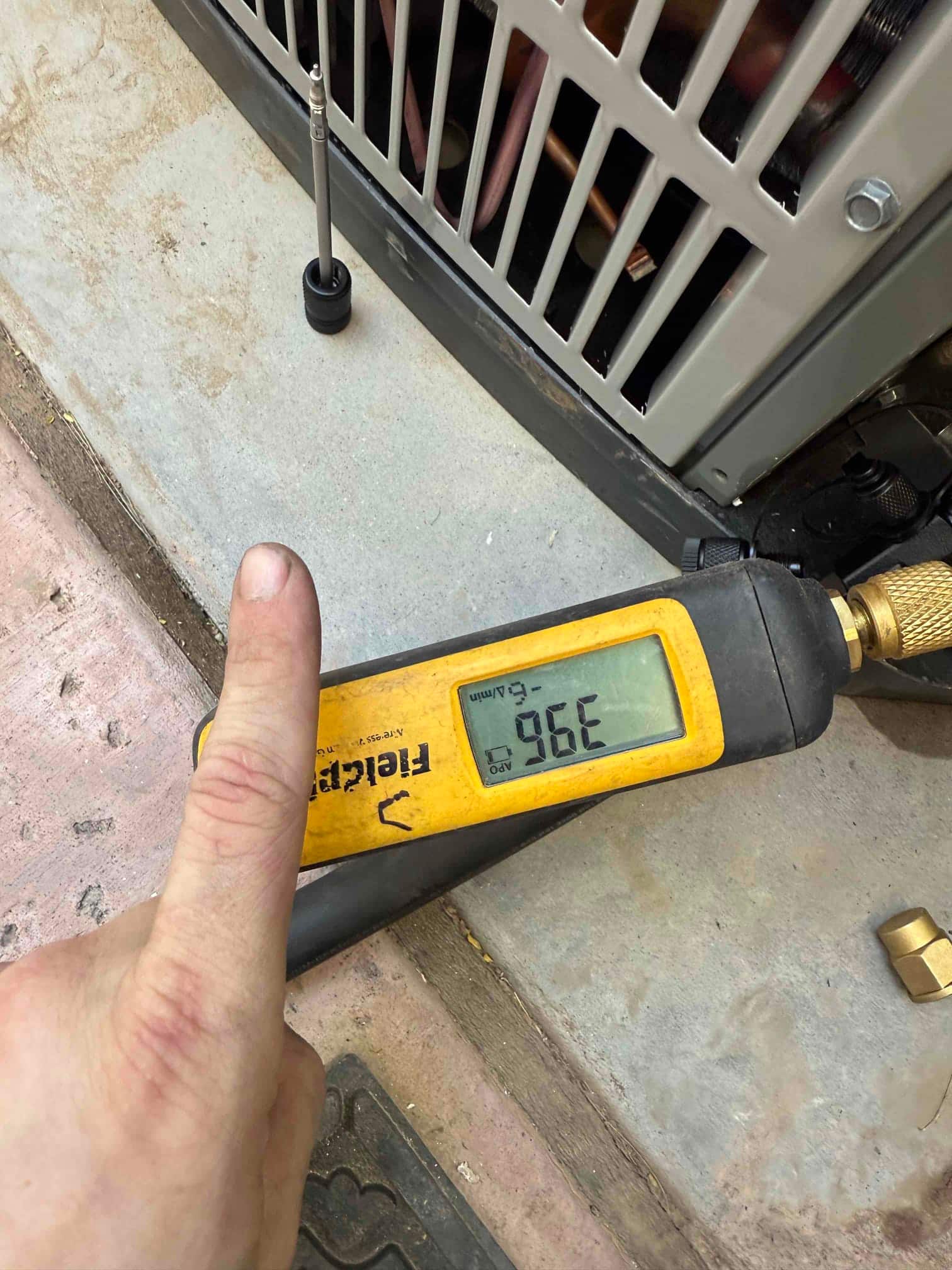 Digital micron gauge connected at the outdoor unit reads 396 microns, confirming a deep system evacuation before refrigerant charging.