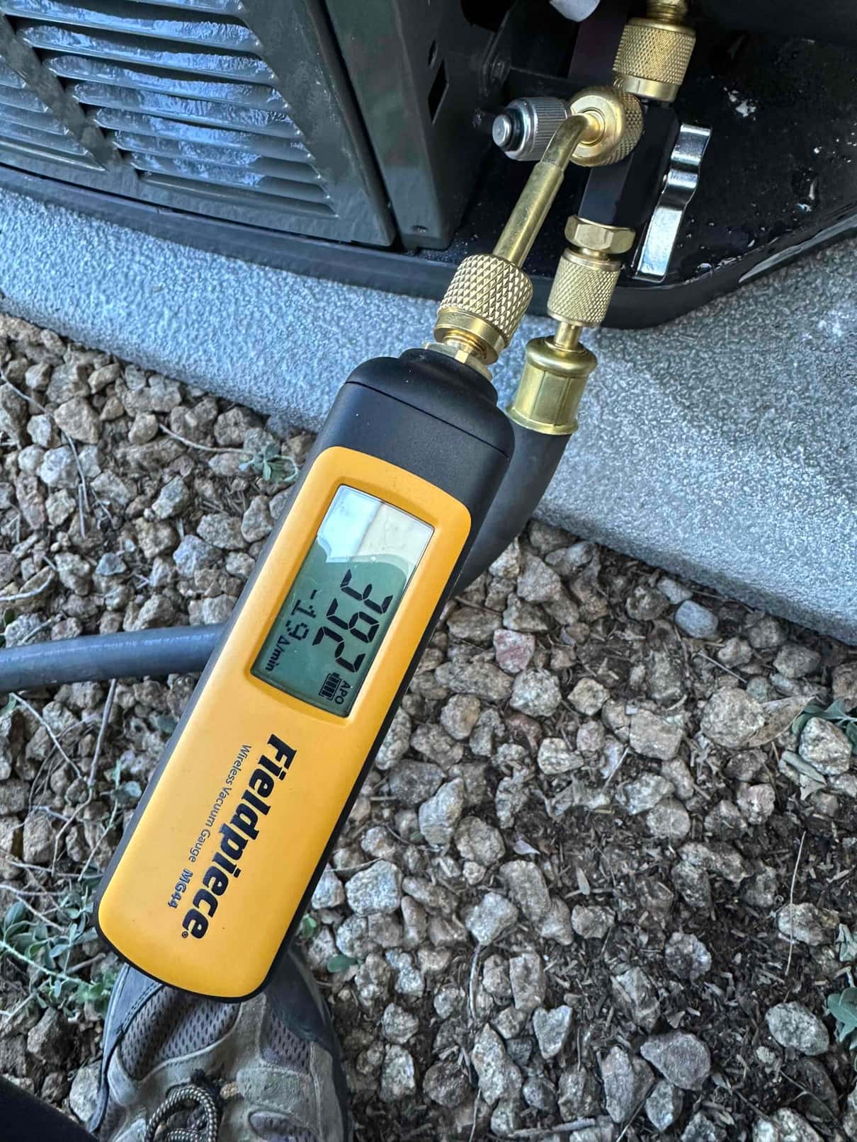 Digital micron gauge connected at the outdoor unit shows a deep vacuum reached during system evacuation.