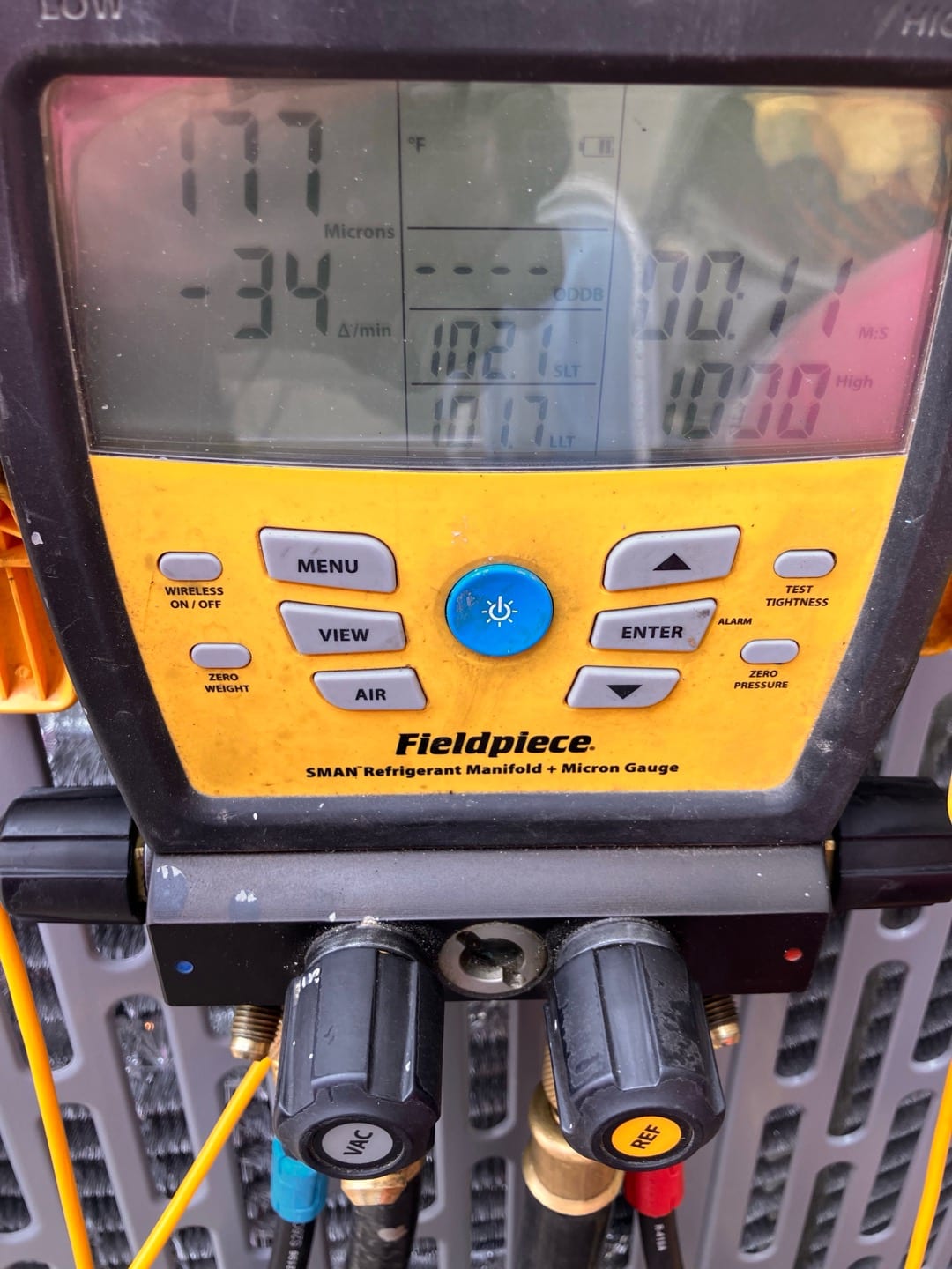 Digital micron gauge on the manifold reads 177 microns, confirming a deep vacuum during system evacuation before charging.