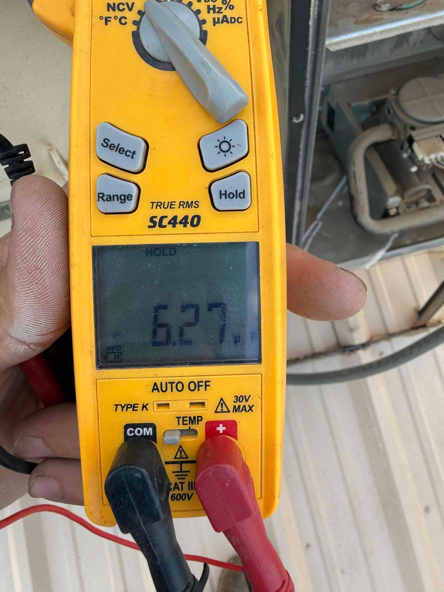 Digital multimeter shows 6.27 V on the display while testing wiring at the outdoor condenser unit.