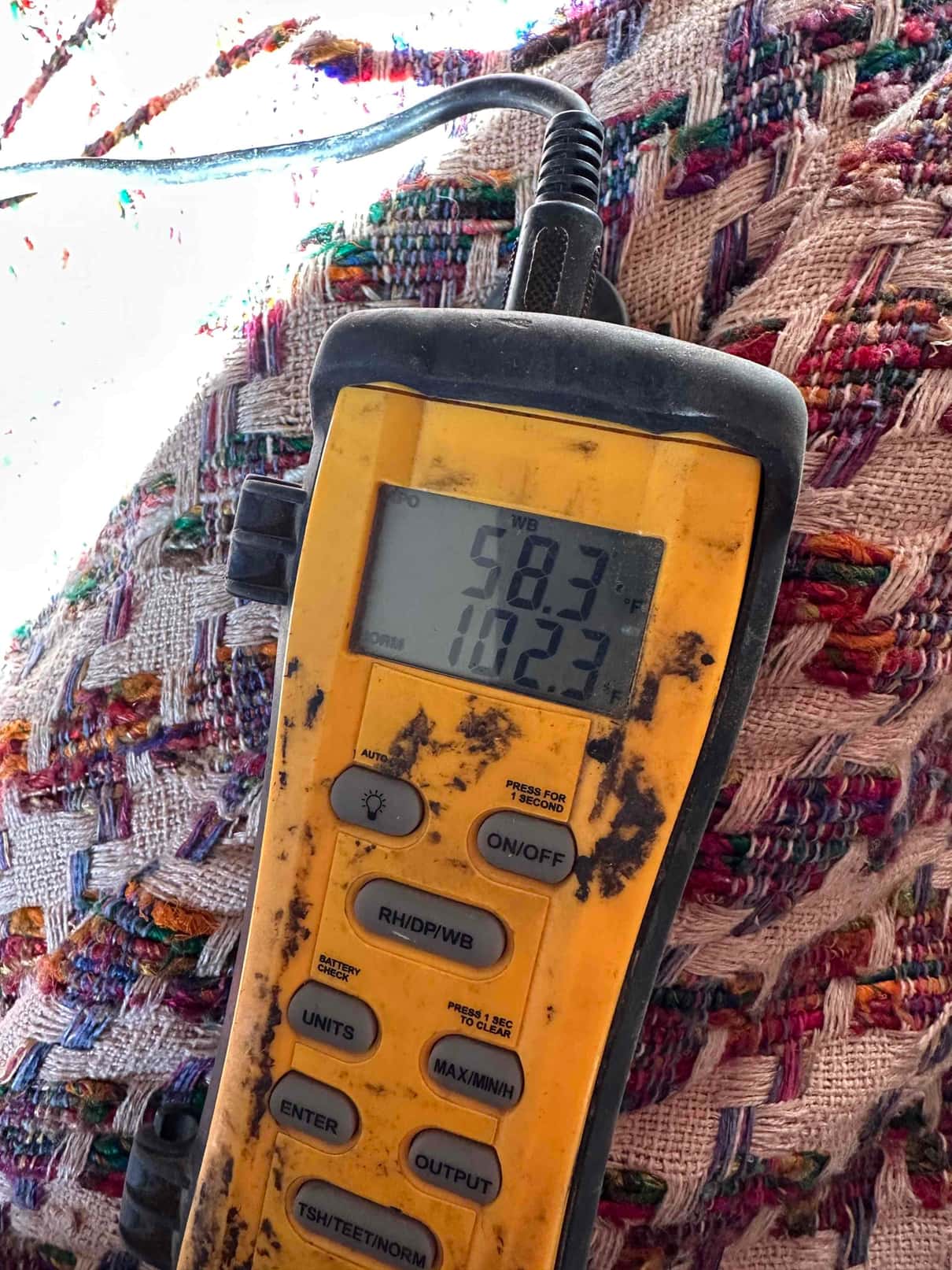 Digital thermometer displays 58.3 degrees on the probe during air temperature testing of the mini-split installation.