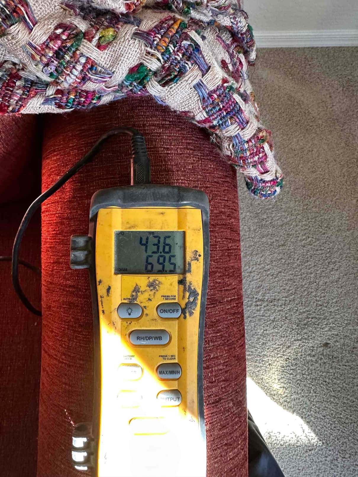 Digital thermometer displays 69.5 degrees Fahrenheit during air temperature check as part of mini-split commissioning.