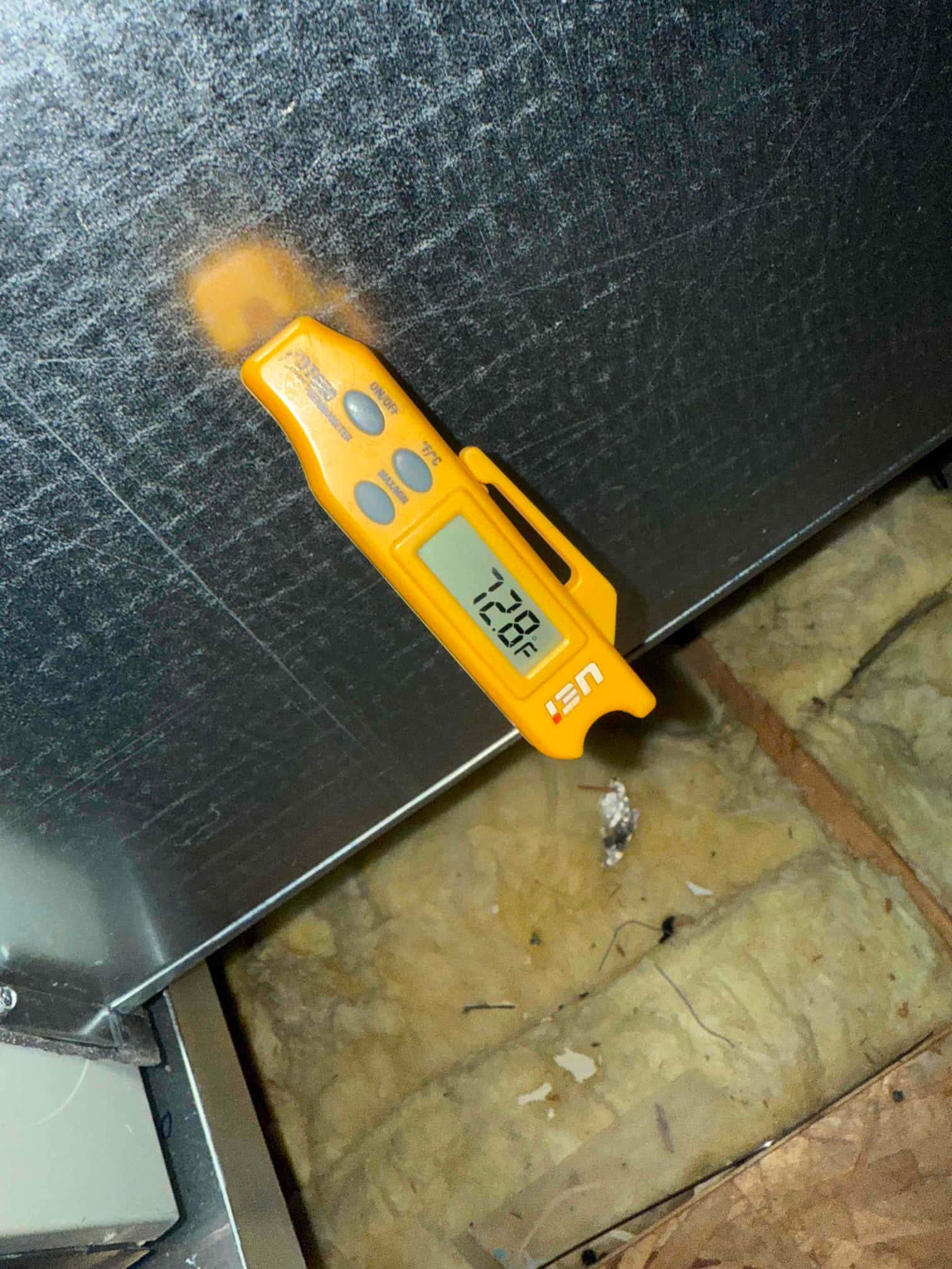 Digital thermometer inserted in duct measures 72.8°F air temperature during commissioning of the installed HVAC system.